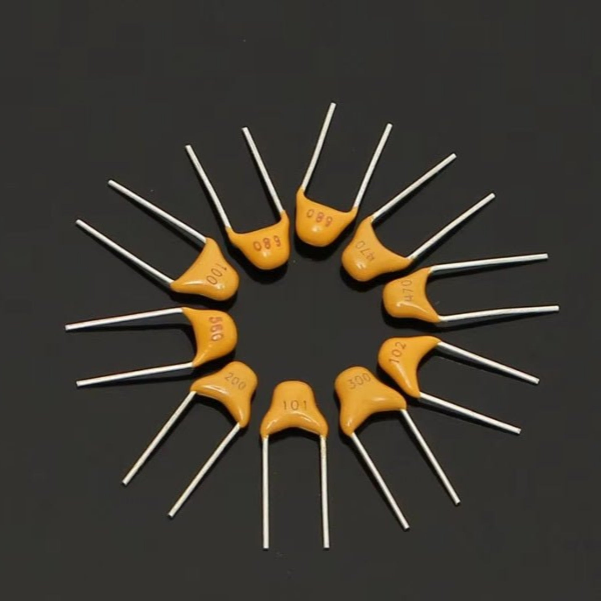 Multilayer ceramic capacitors arranged in a circular pattern, showcasing different values and metal leads.