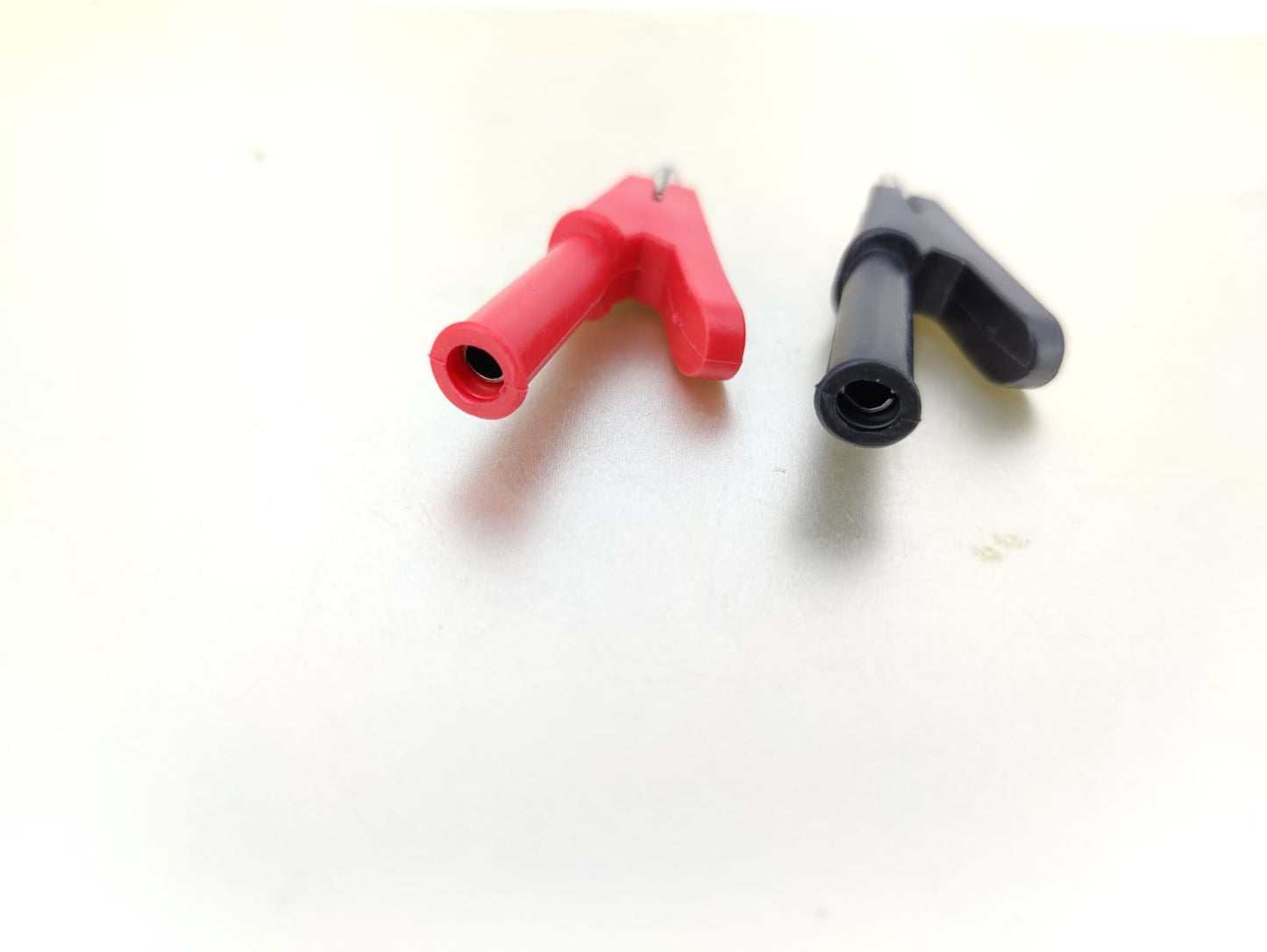 Close-up of red and black 20A crocodile alligator clips with 4mm banana plug receptacles, ideal for electrical connections.