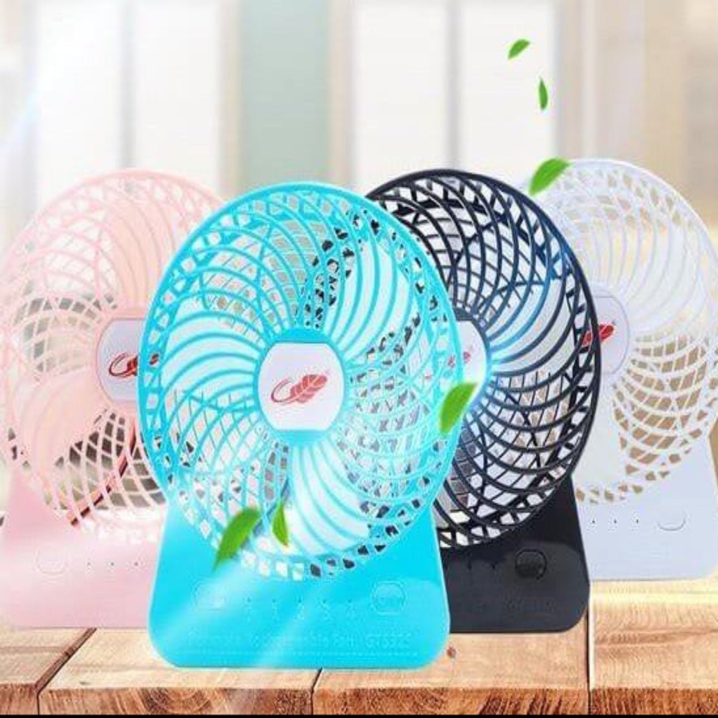 Colorful 6-inch portable rechargeable fans in pink, blue, black, and white on a wooden table, designed for convenience.