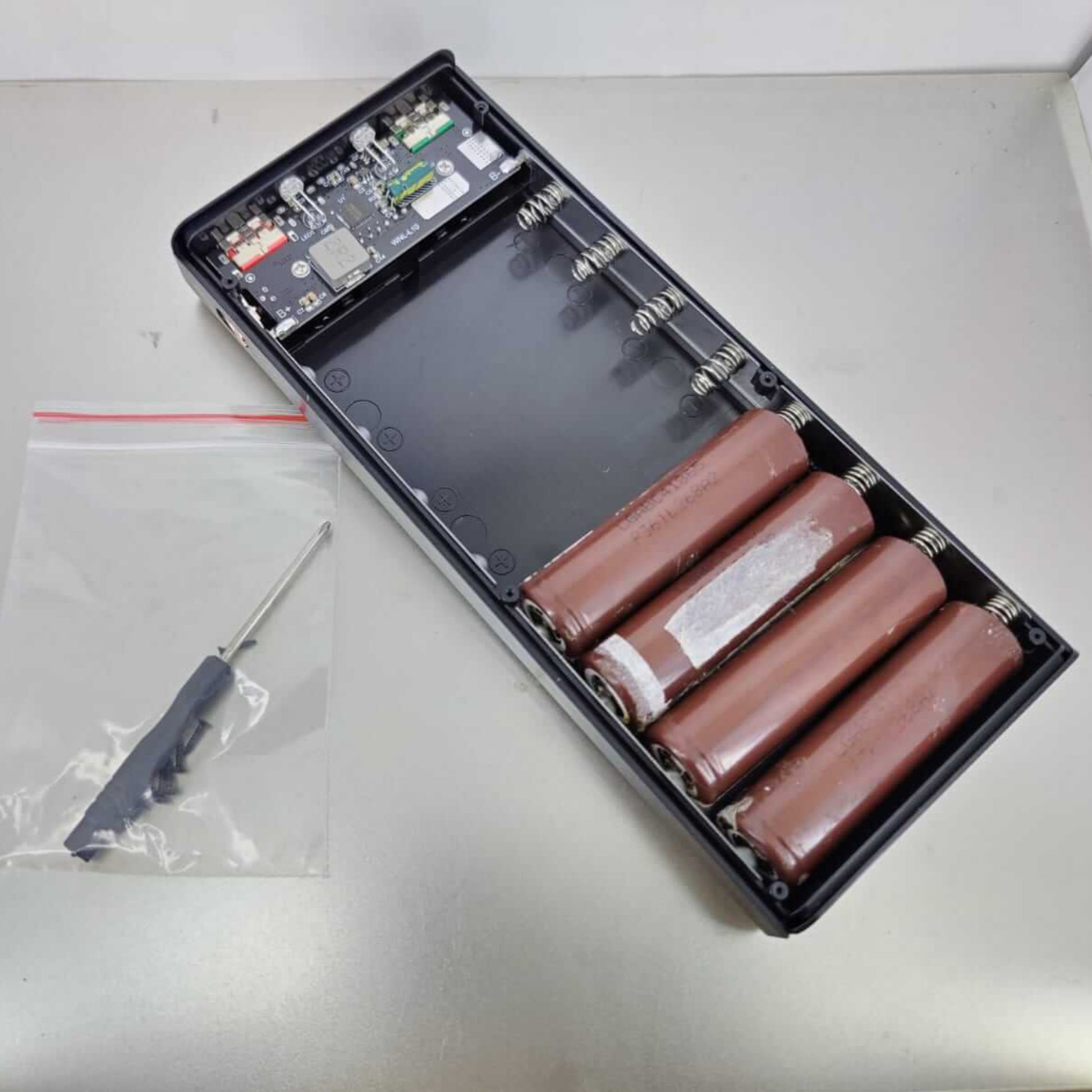Complete DIY kit for PD22.5W power bank case, shown with screwdriver, screws, and four 18650 batteries ready for installation.