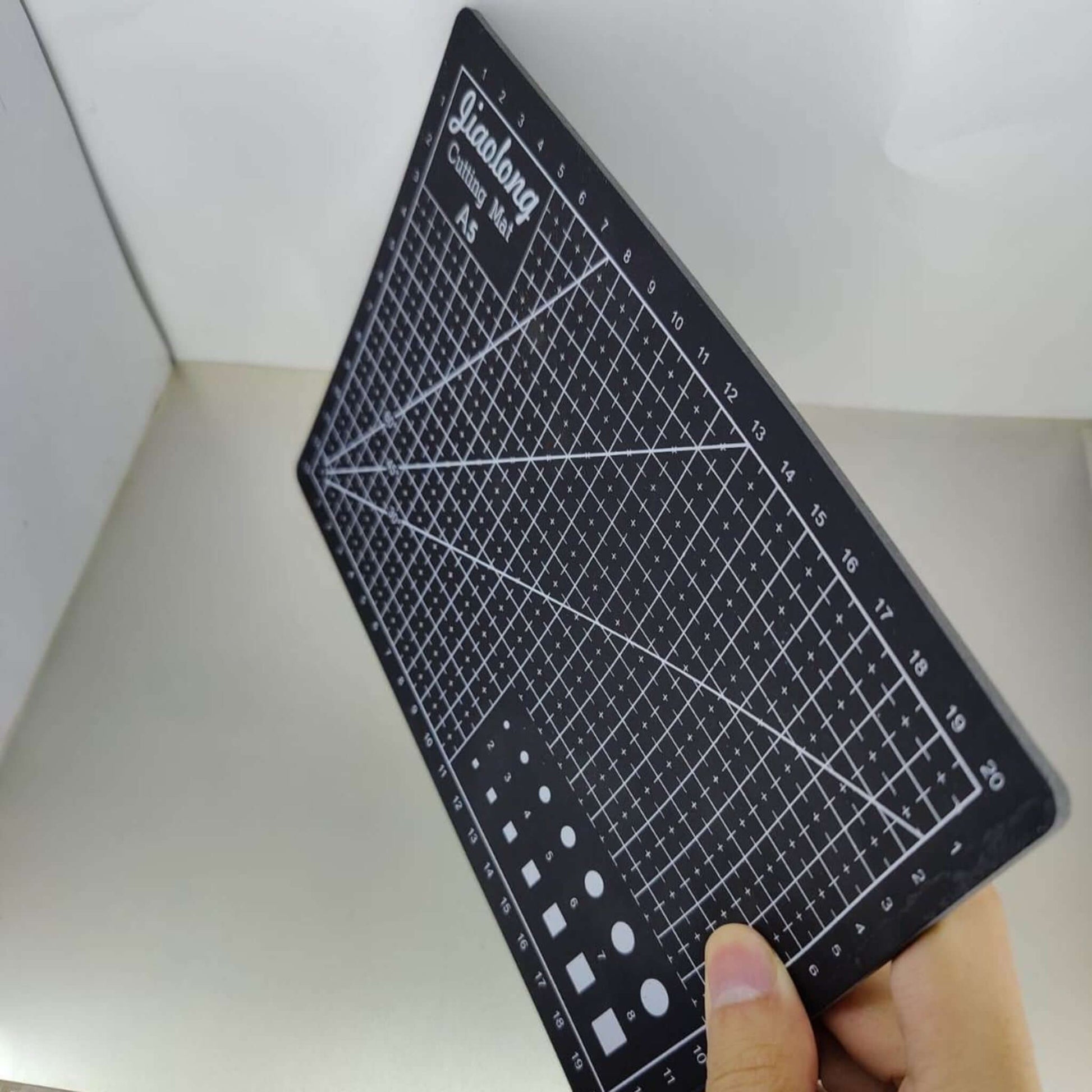 A5 rotary cutting mat shown in hand, designed for sewing, quilting, and crafting with engraved guidelines.