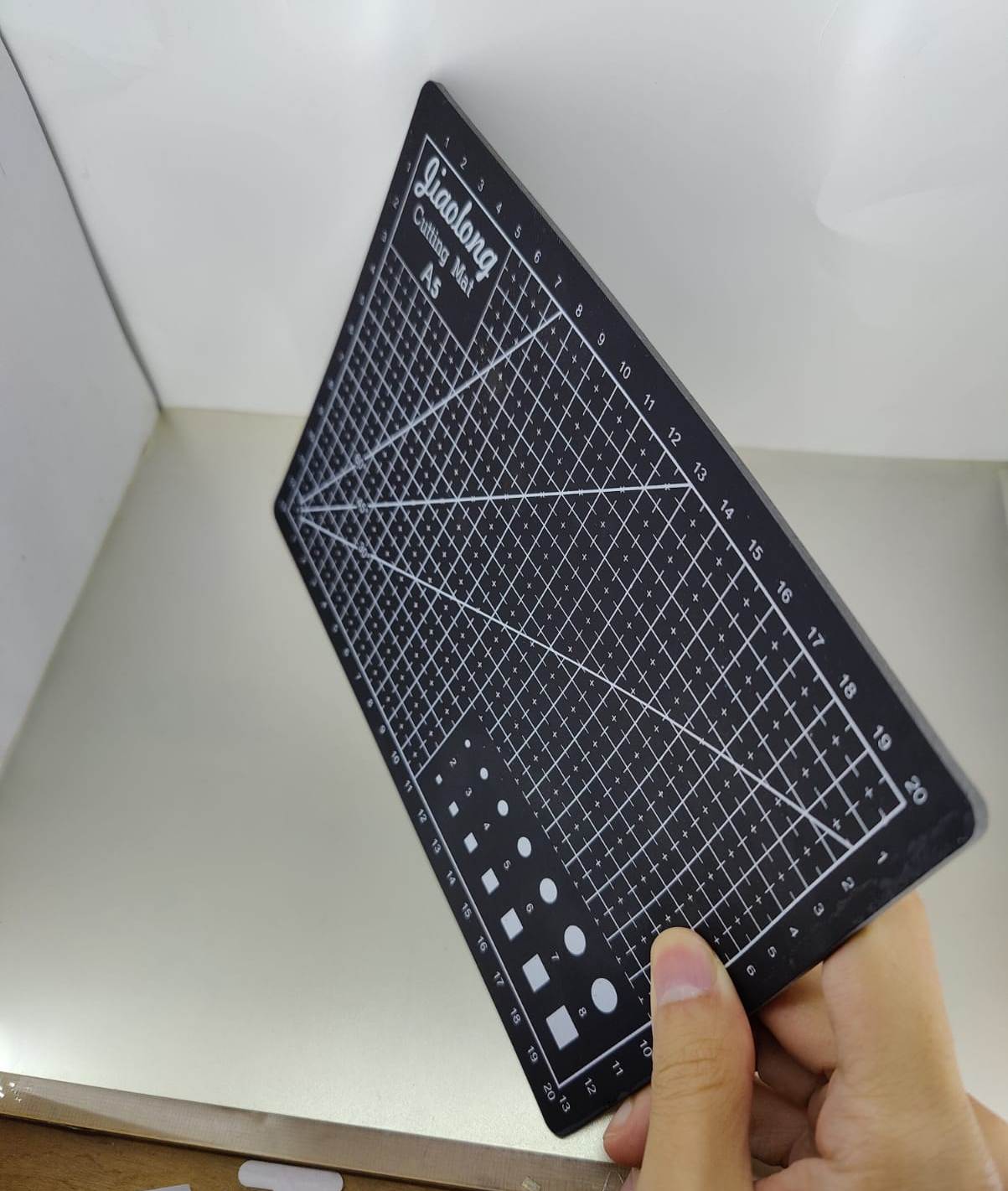 A5 rotary cutting mat shown in hand, designed for sewing, quilting, and crafting with engraved guidelines.