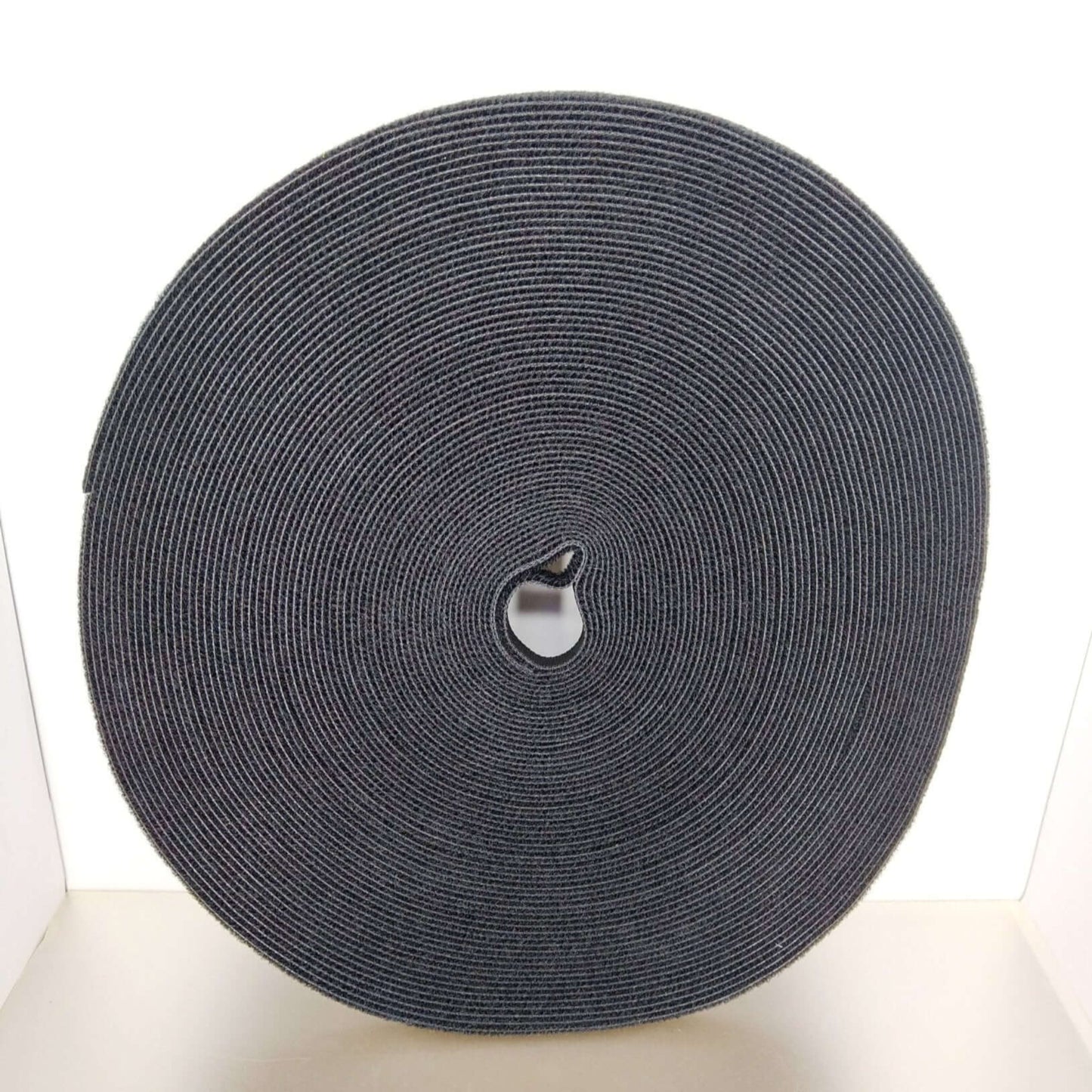 Black hook and loop tape roll, 1cm x 25m, for heavy duty cable management and wire organization.