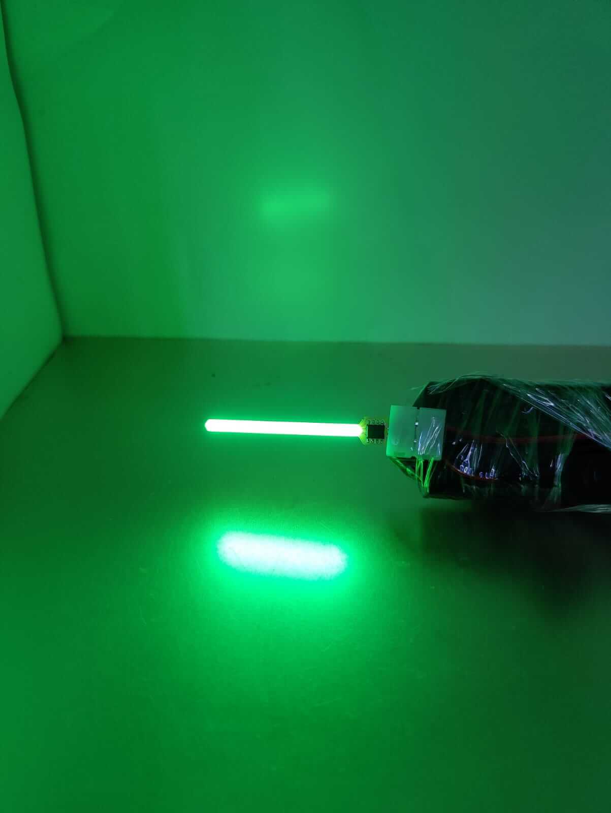 Green LED light emitting from a sleek tube lamp, showcasing vibrant glowing effect on a reflective surface.