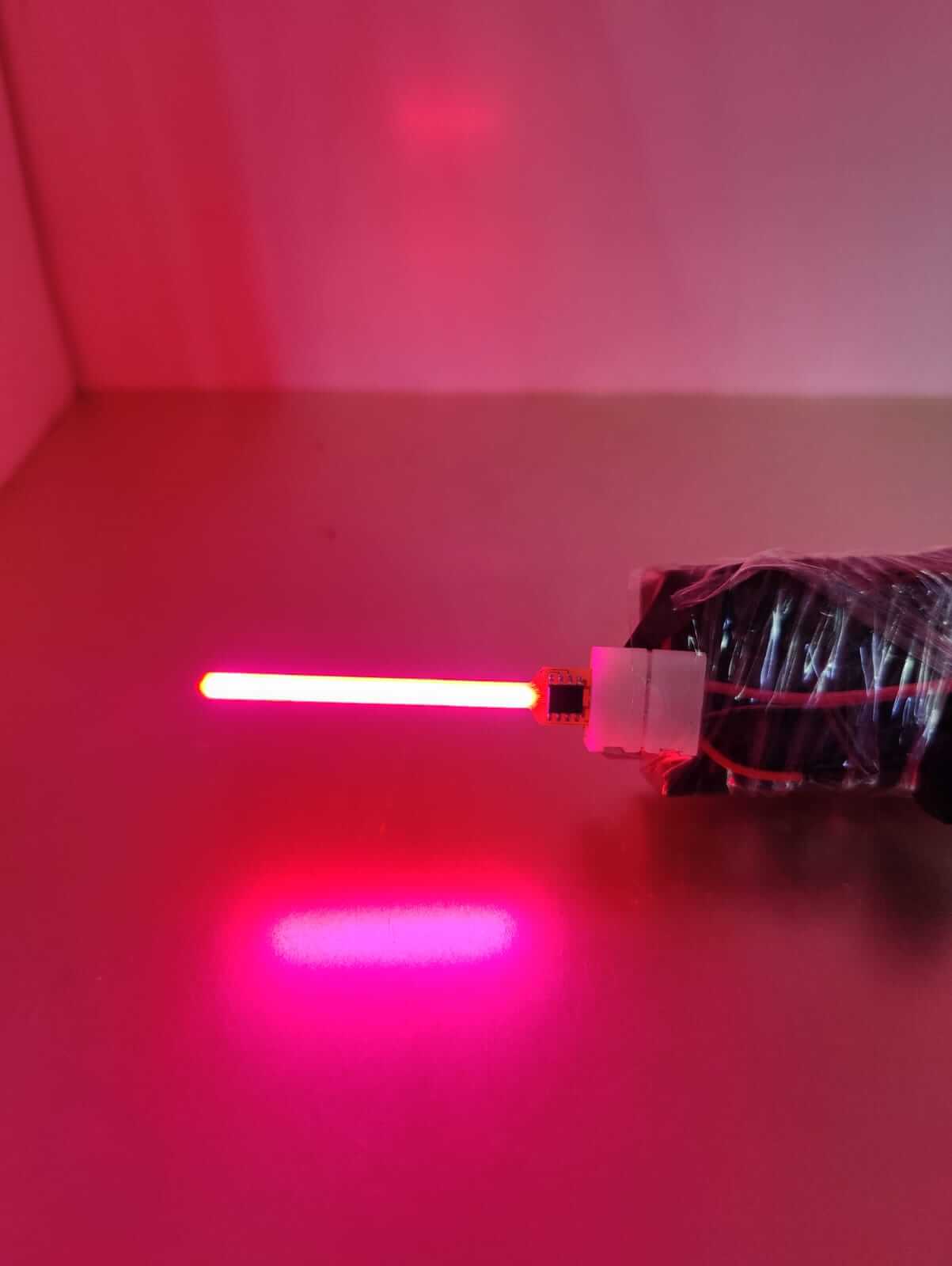 Close-up of a glowing red LED lamp filament emitting vibrant light, showcasing modern lighting design.