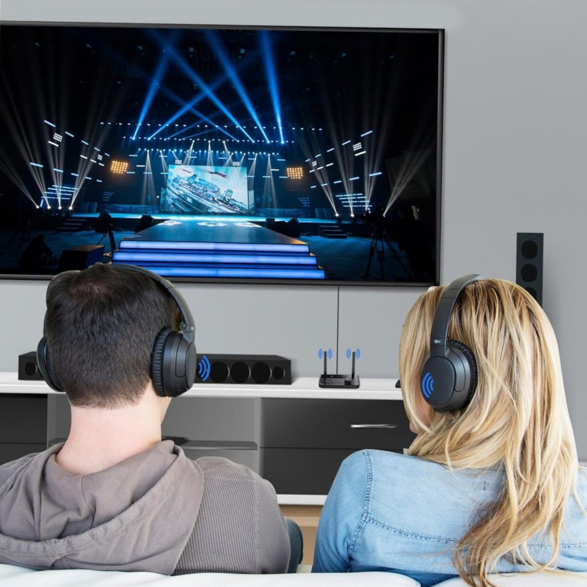 Couple using Bluetooth headphones to enjoy audio from a TV in a cozy living room setting.