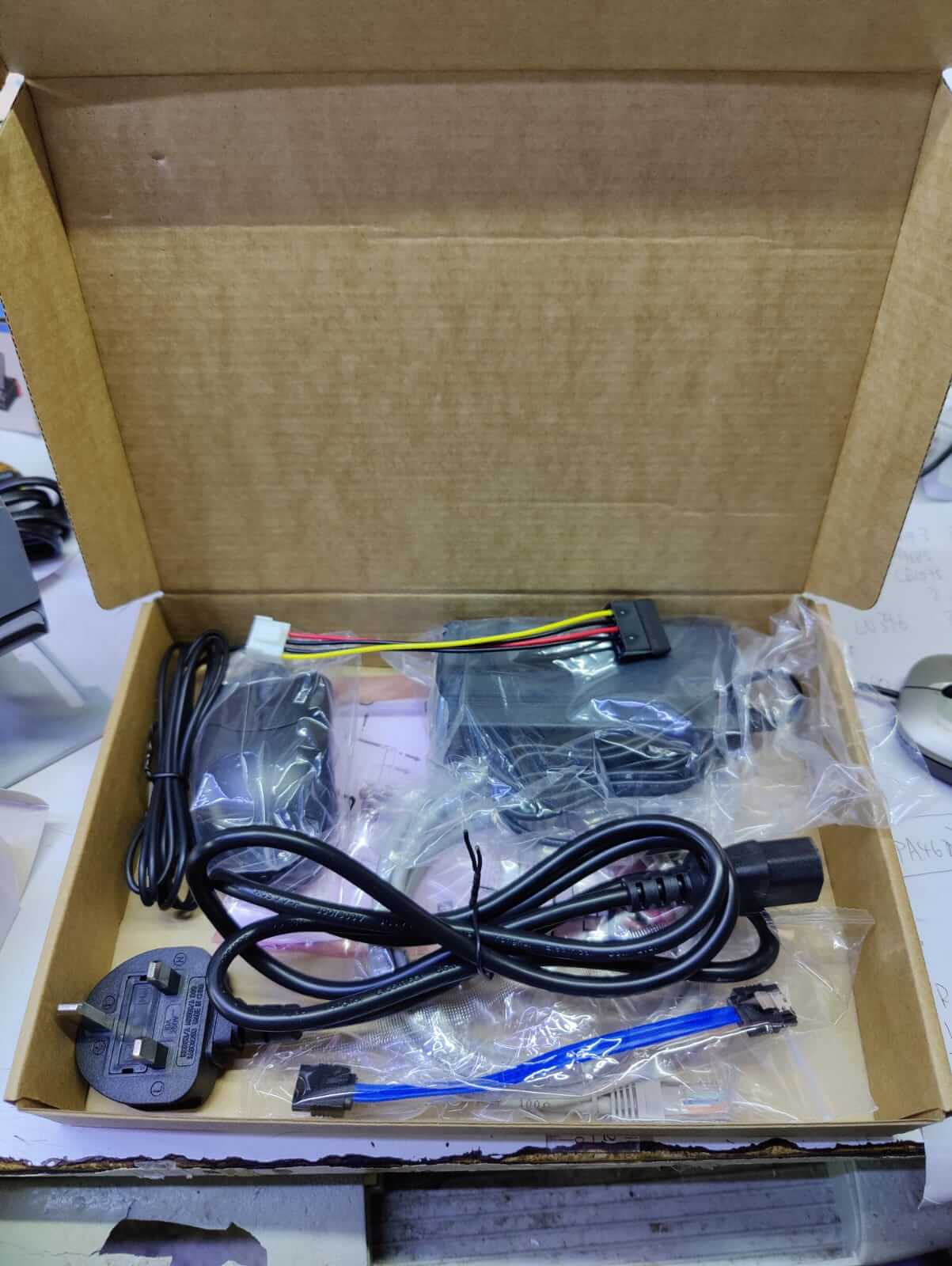 Open box showing cables and components for Dahua NVR2104HS-P-4KS3 installation and setup.