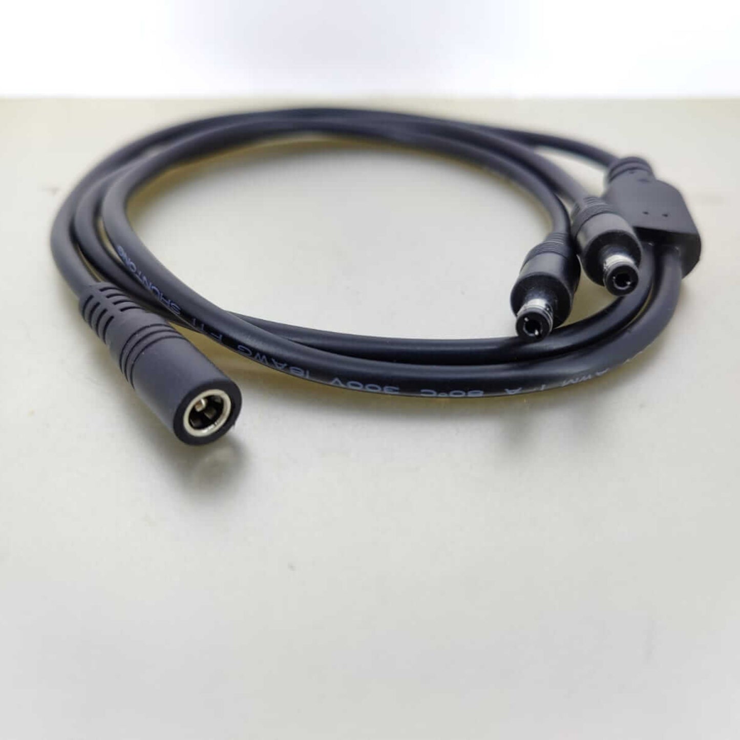 DC power cable splitter with one female 5.5mm x 2.1mm connector and two male connectors.