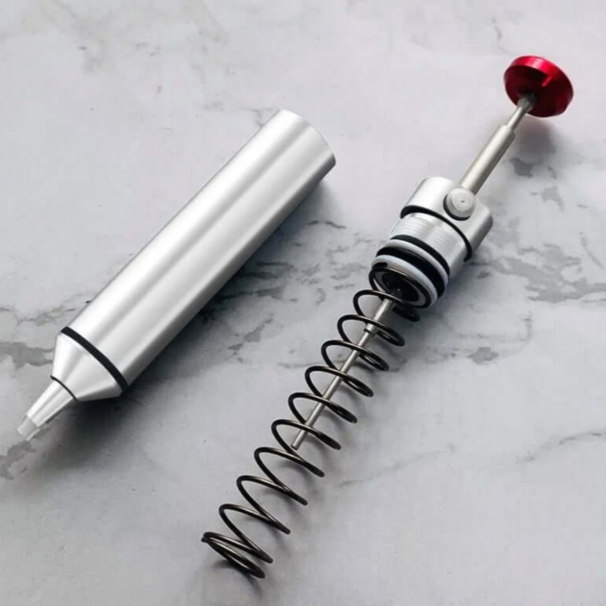 The desoldering pump disassembled to show the internal spring-loaded piston mechanism, highlighting it is easy to clean.