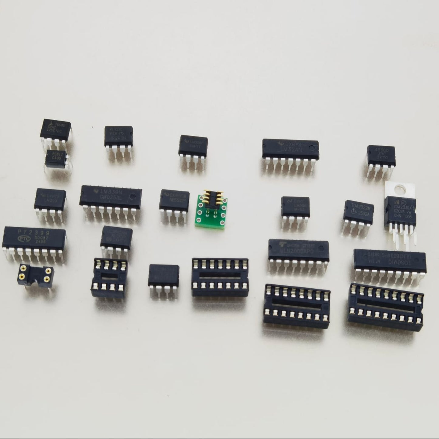 Close-up display of loose IC chips including TDA2030A, ULN2003AN, and DIP sockets on a white background.