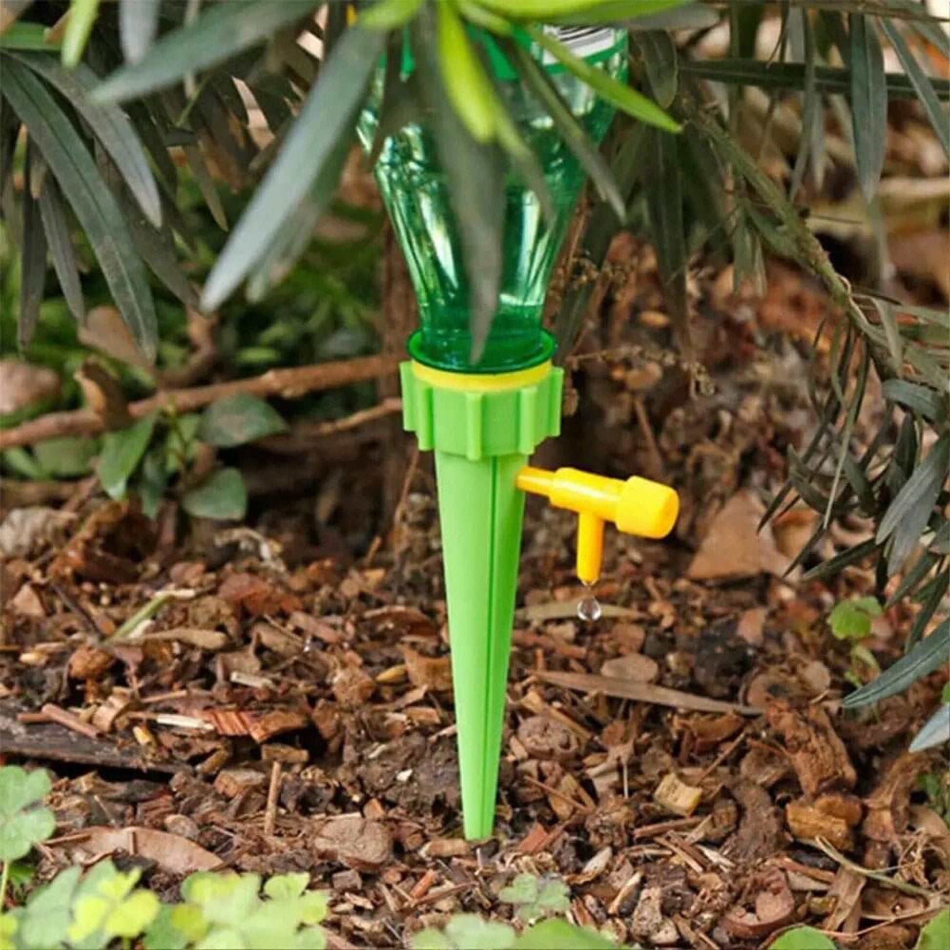 Automatic drip self-watering spike for plants with adjustable flow control, inserted in garden soil.