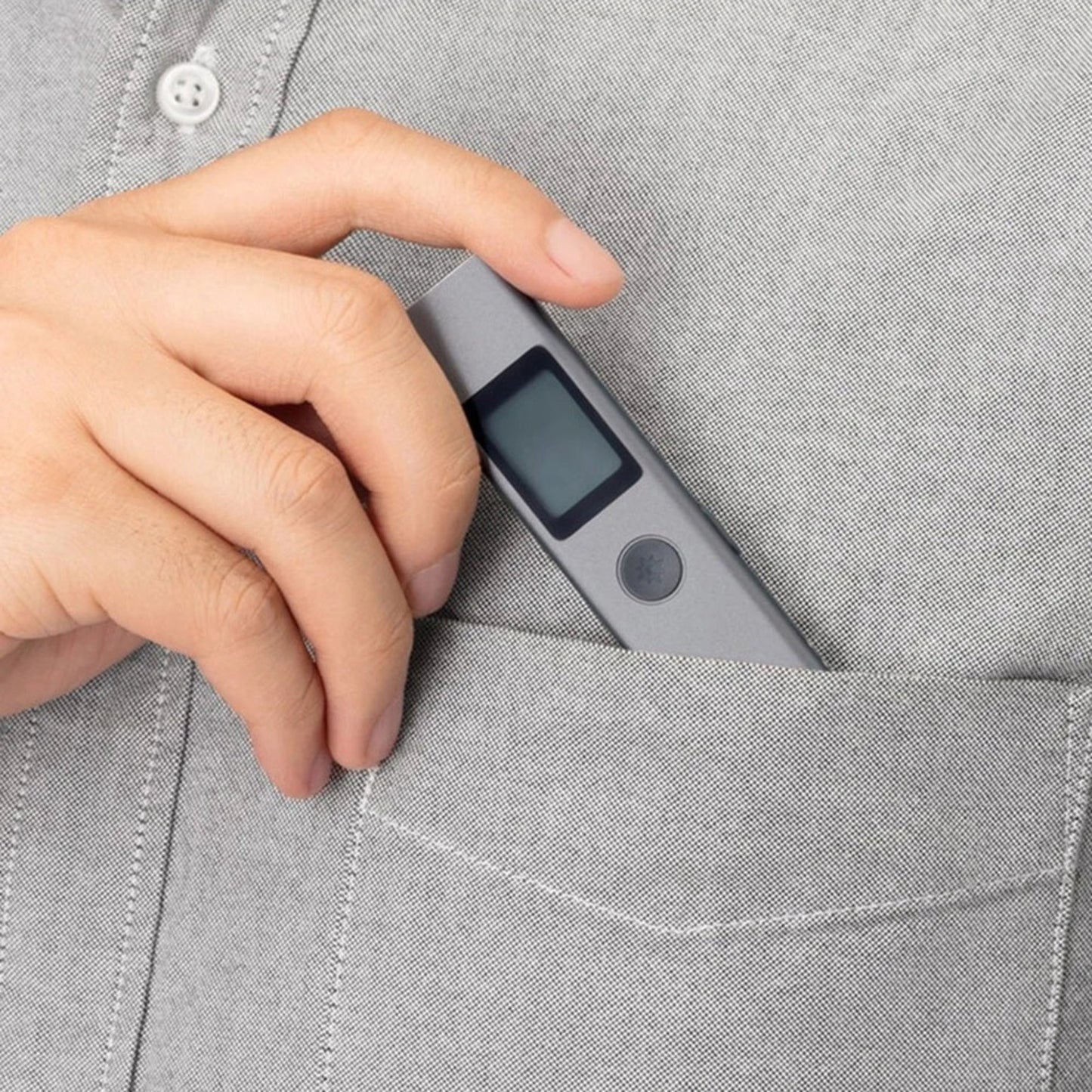 Person holding Duka LS-P laser range finder, compact and portable, designed for easy storage in a shirt pocket.