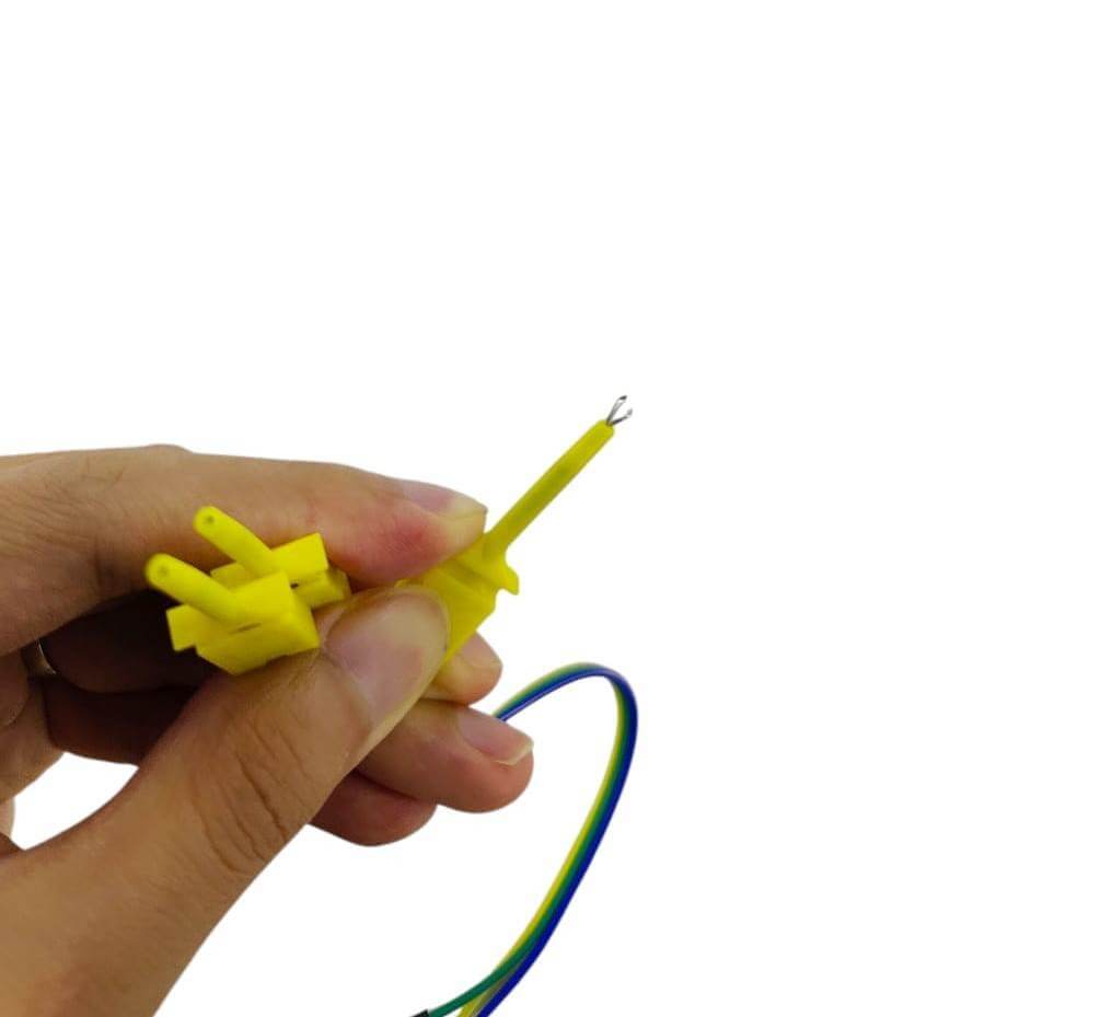 Hand holding yellow logic analyzer test hook clip with Dupont jumper wires for electronics testing.