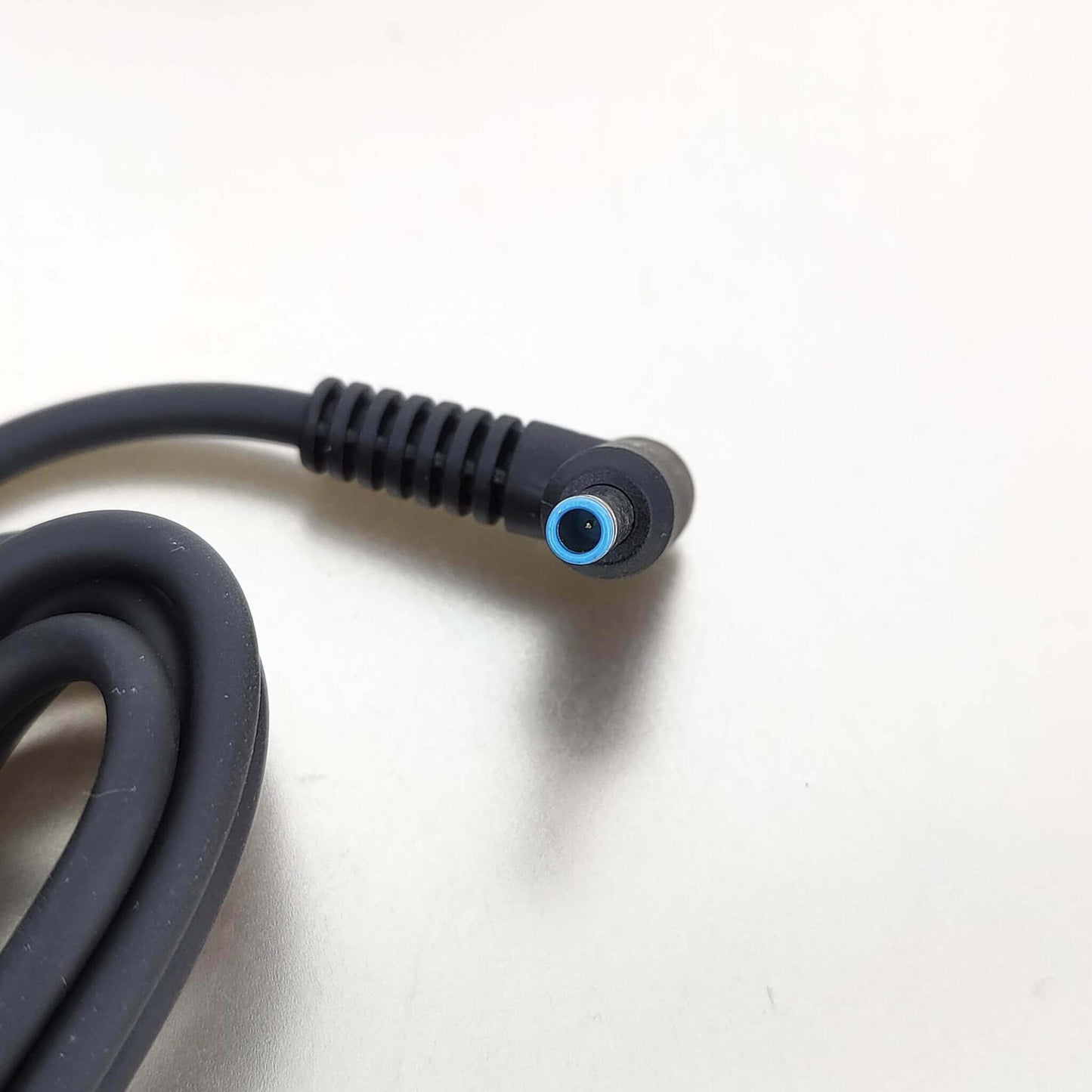 Close-up of HP laptop charger's 4.5mm x 3.0mm blue tip DC connector, highlighting compatibility.