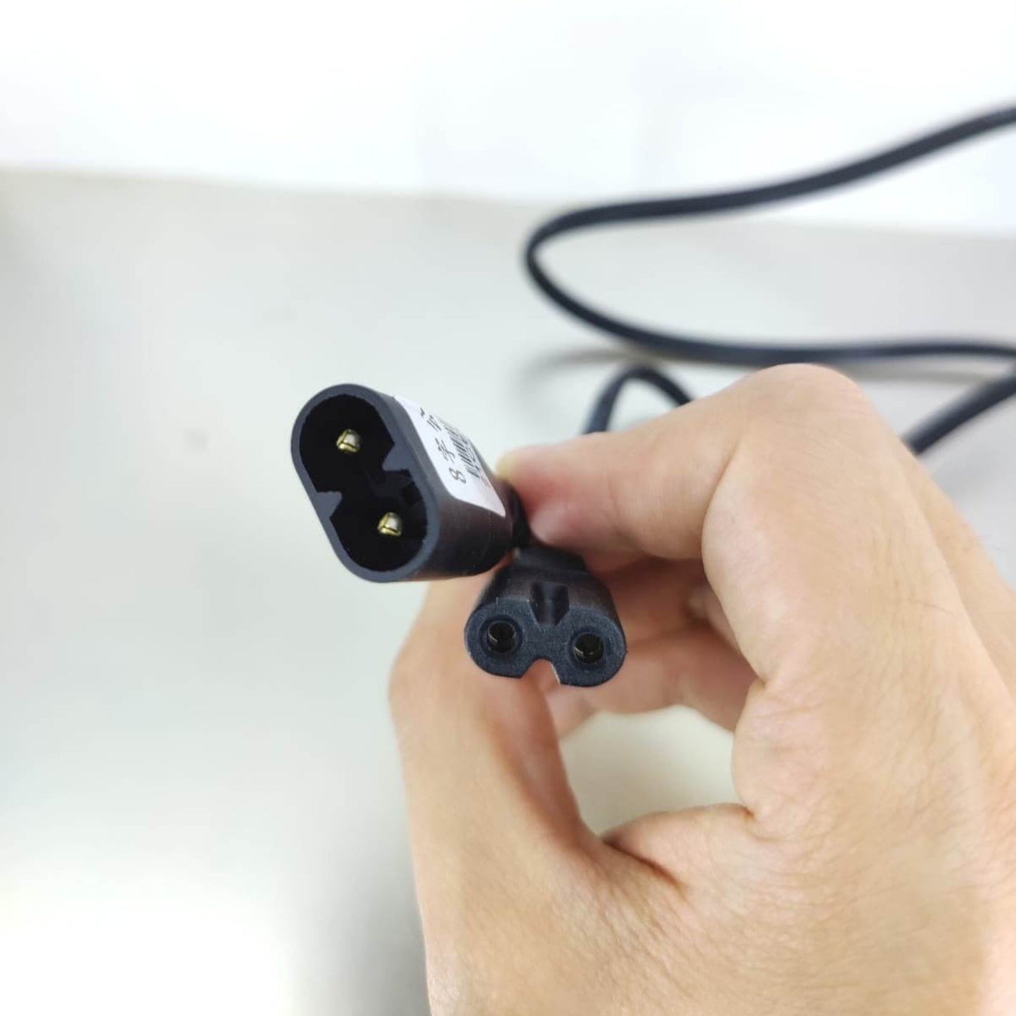 Figure 8 extension power cable showing C8 male and C7 female connectors in a person's hand.