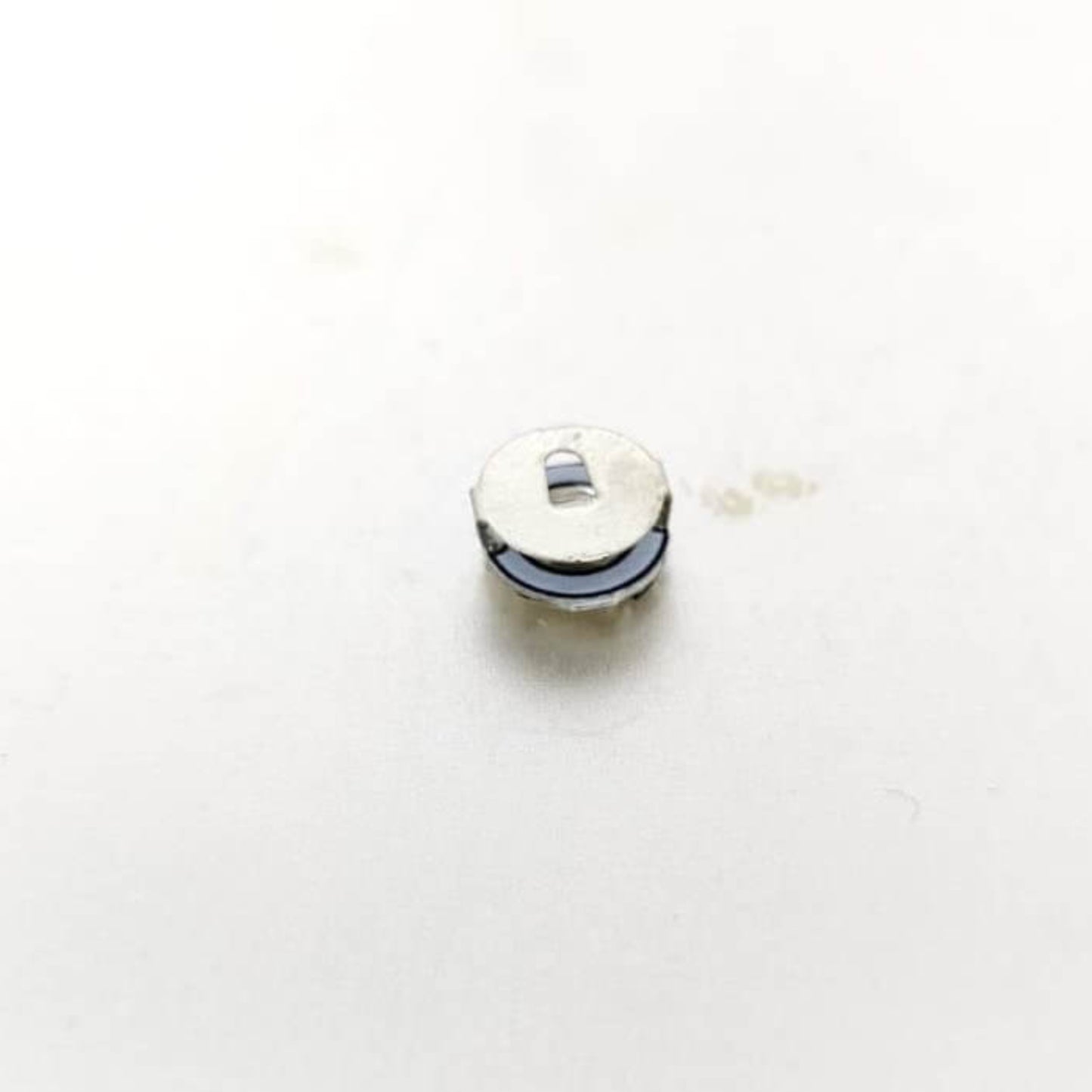 Close-up of a small, round LED light battery for Mini Magnetic Control LED Lamps in DIY projects.