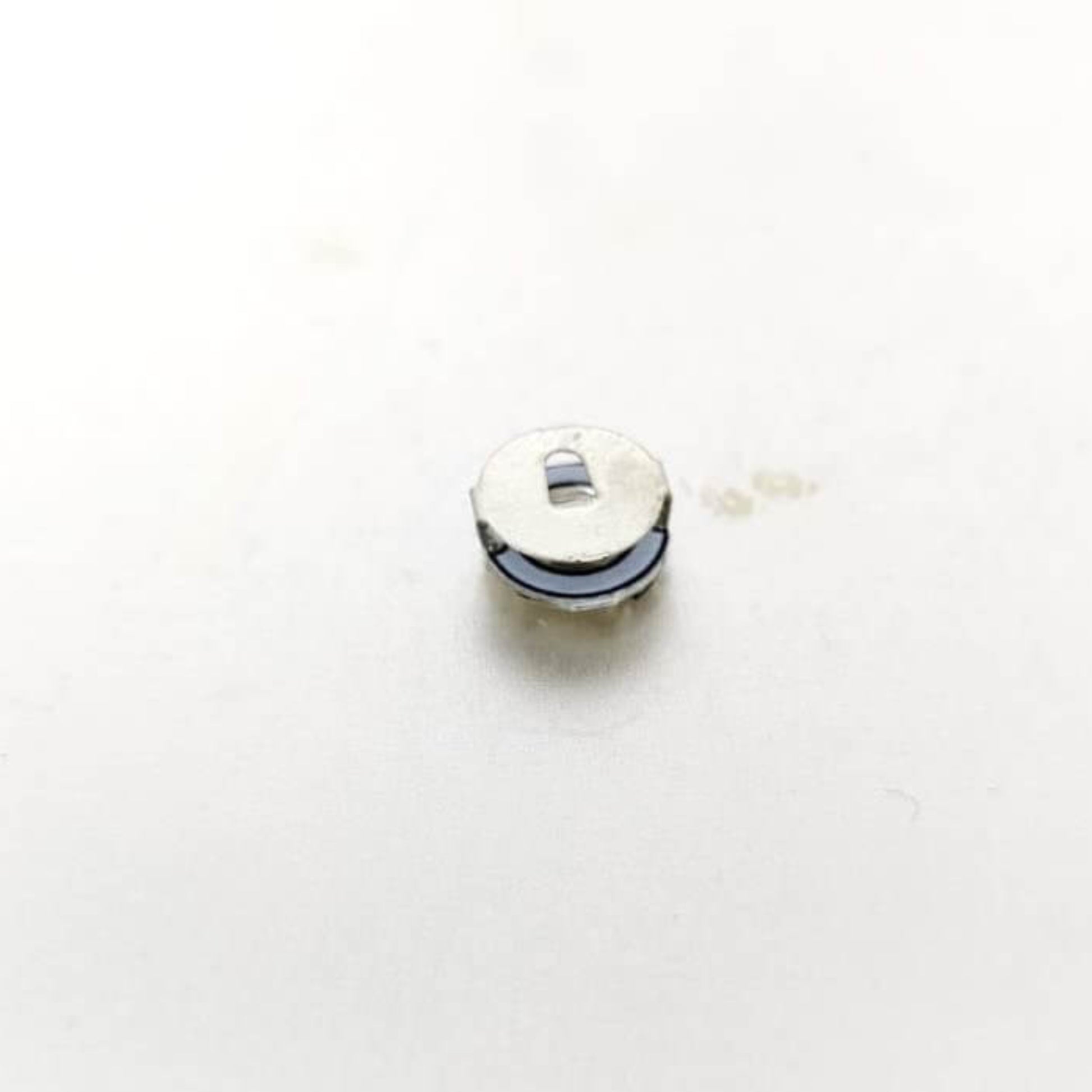 Close-up of a small, round LED light battery for Mini Magnetic Control LED Lamps in DIY projects.