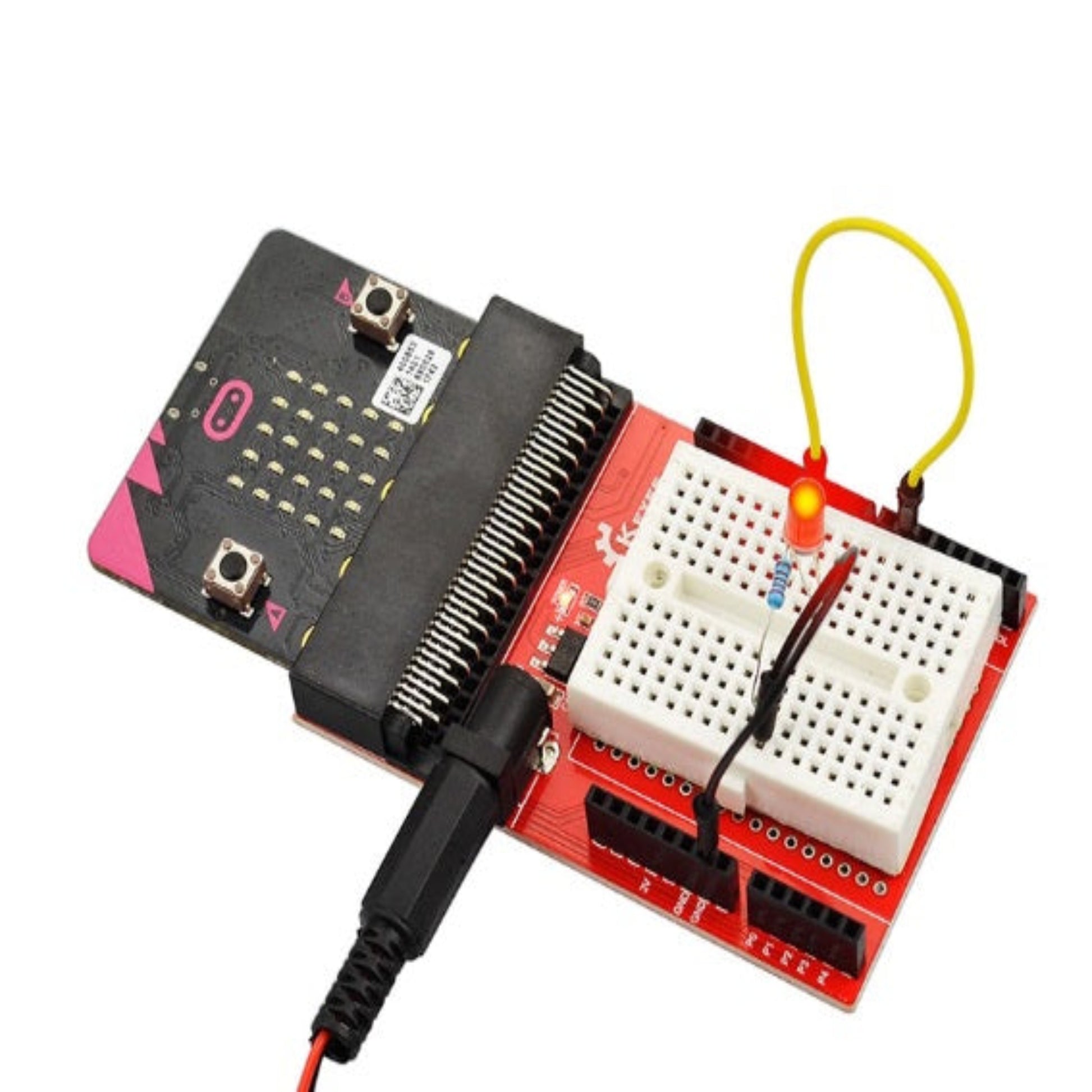 A micro:bit board plugged into a red IO expansion shield, with a simple LED circuit connected on the attached white breadboard.