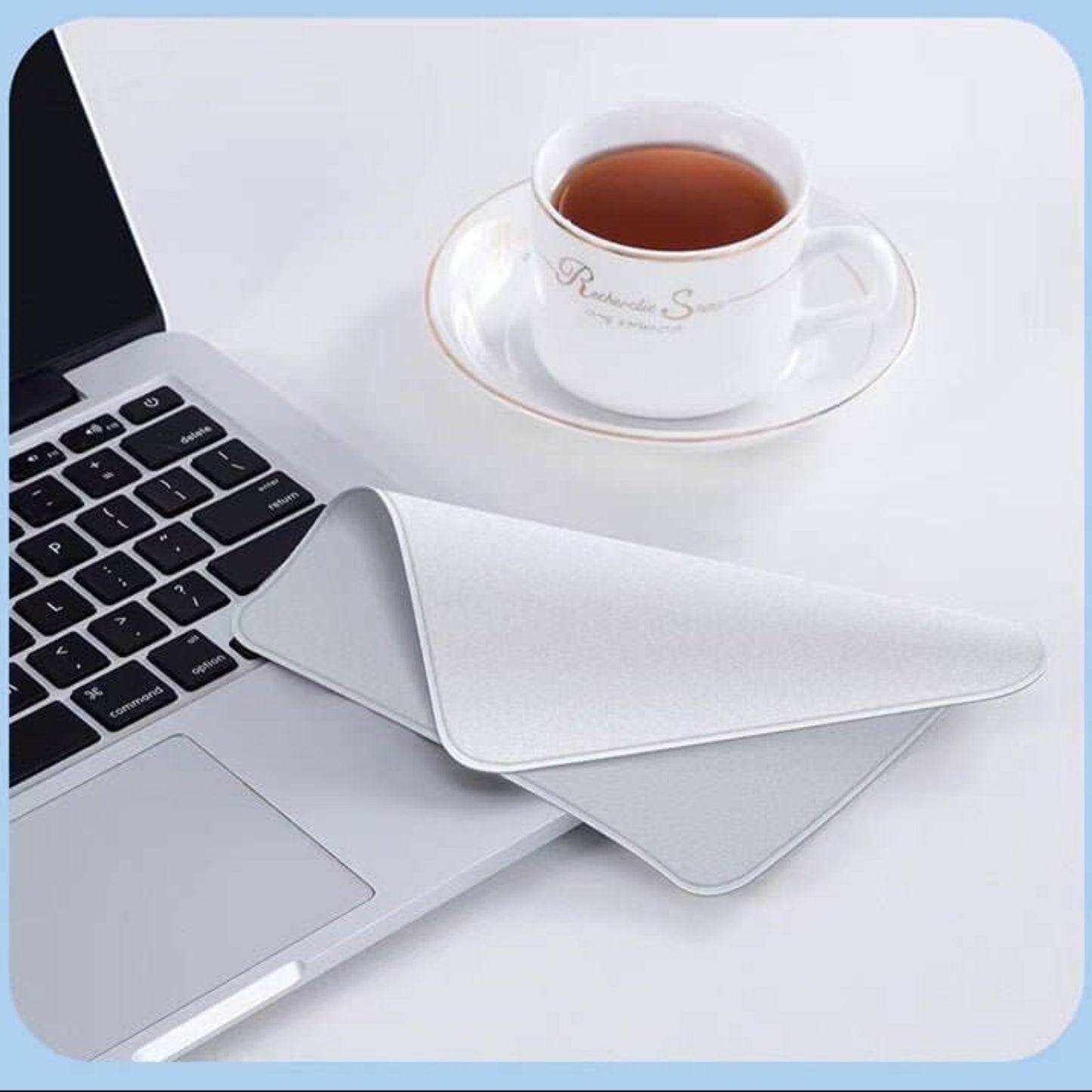 Soft microfiber polishing cloth for Apple devices, placed beside a laptop and tea cup.