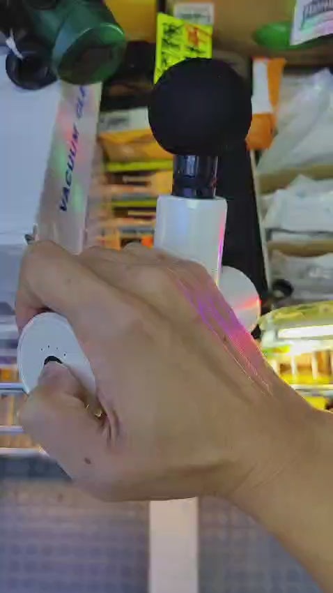 Hand holding a mini portable percussion massage gun with black head, showcasing its ergonomic design and versatility.