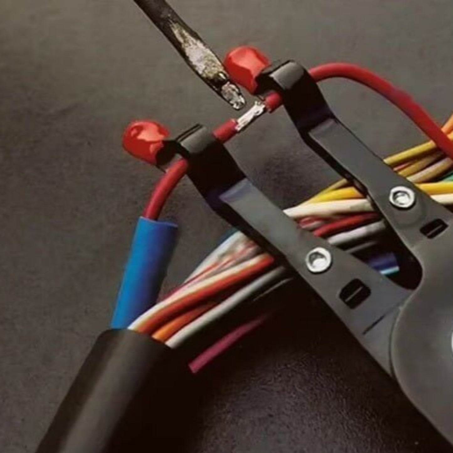 Soldering pliers securely holding wires together during welding process, ideal for auto maintenance and repair.