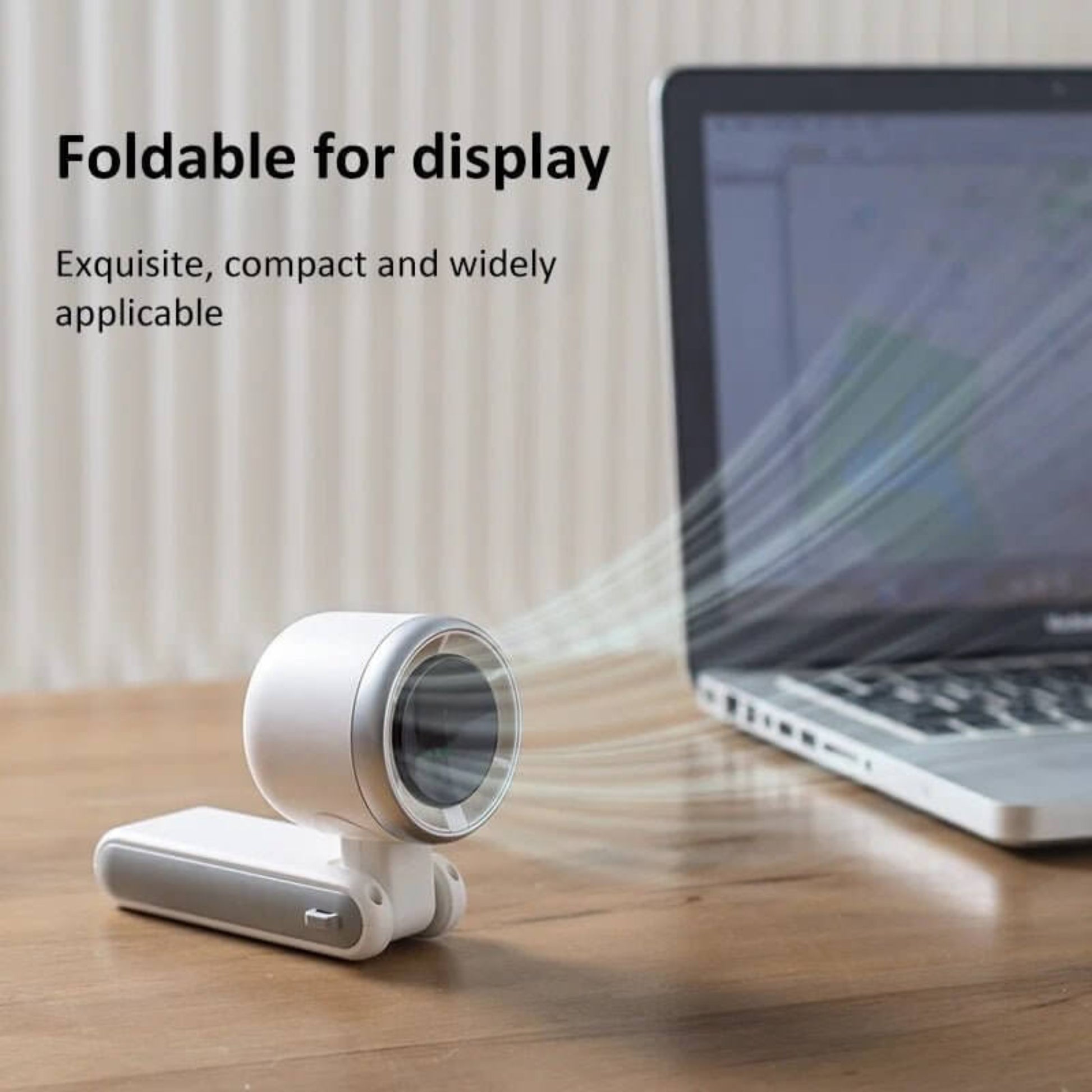 Compact white portable folding turbo fan in desk stand mode, placed next to a laptop for cooling.