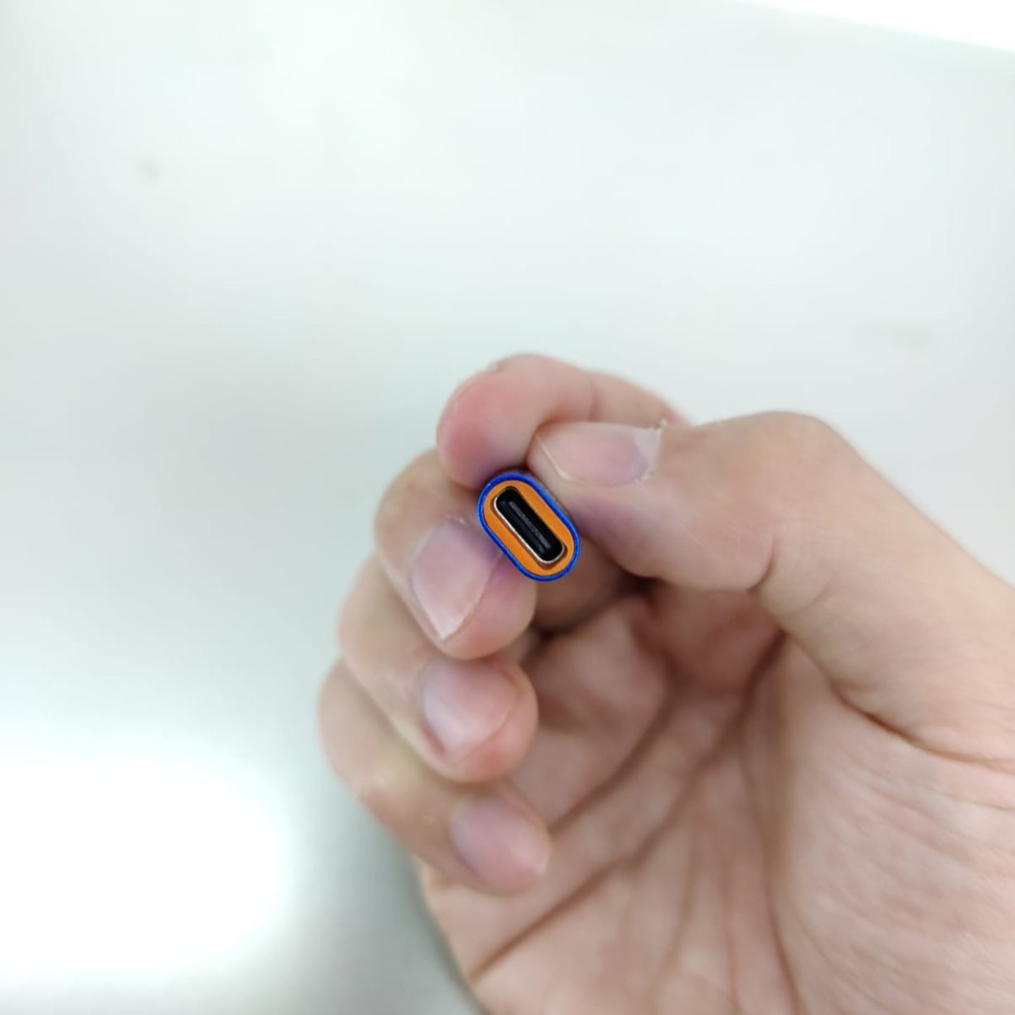 Hand holding a USB-C connector, demonstrating the Type-C to iPhone Lightning adapter connection.