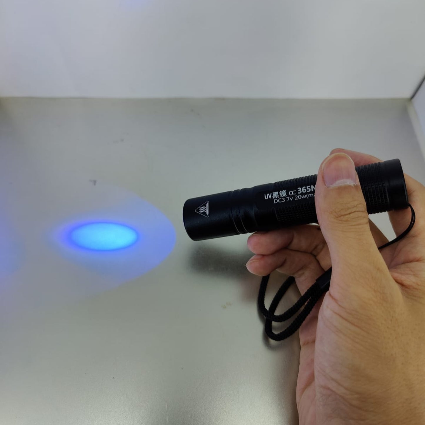 Person holding a rechargeable UV flashlight emitting a 365nm light on a surface, ideal for rock hunting and pet urine detection.