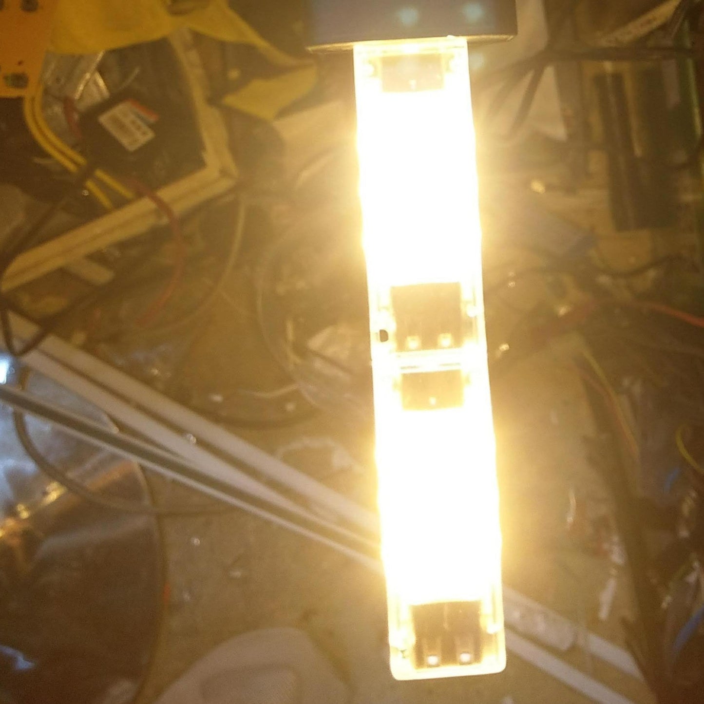 A 12-LED USB light emitting a powerful warm white glow while plugged into a Sony USB power adapter.