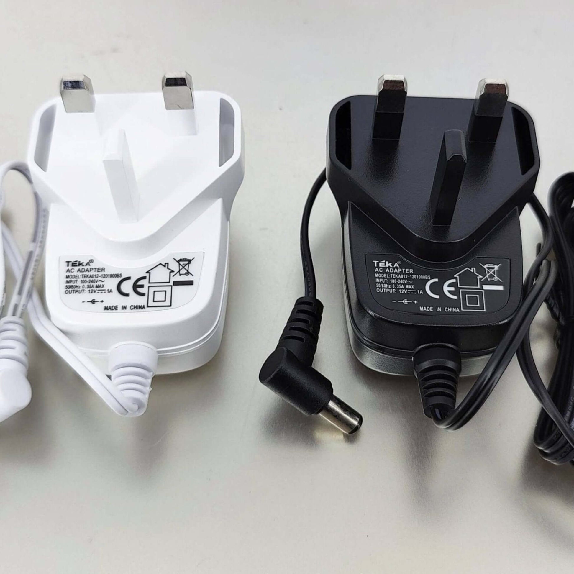 12V 1A DC power adapters with UK plug, featuring white and black designs alongside charging cables.