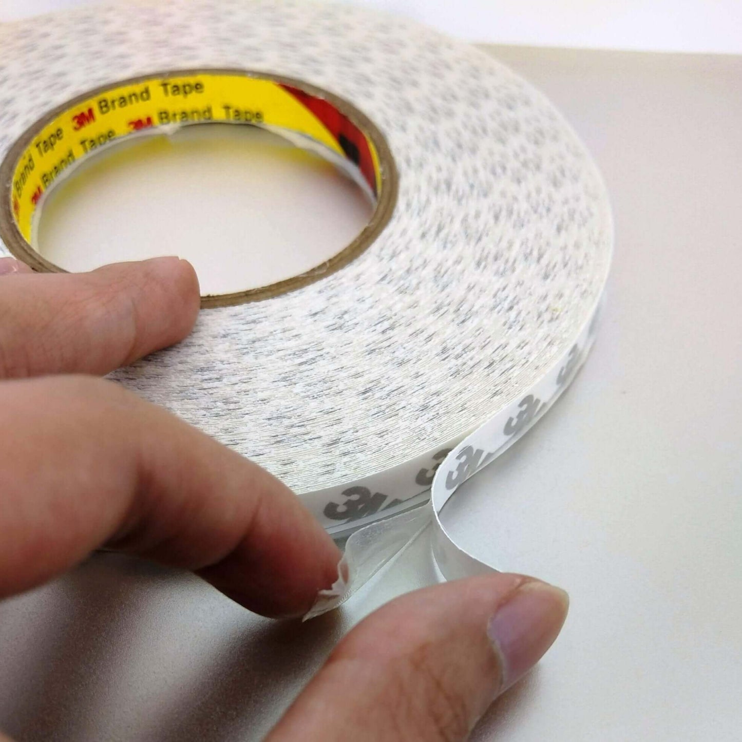 Person holding a roll of 3M Double Sided Tape, showcasing its strong adhesive properties for crafts and DIY projects.