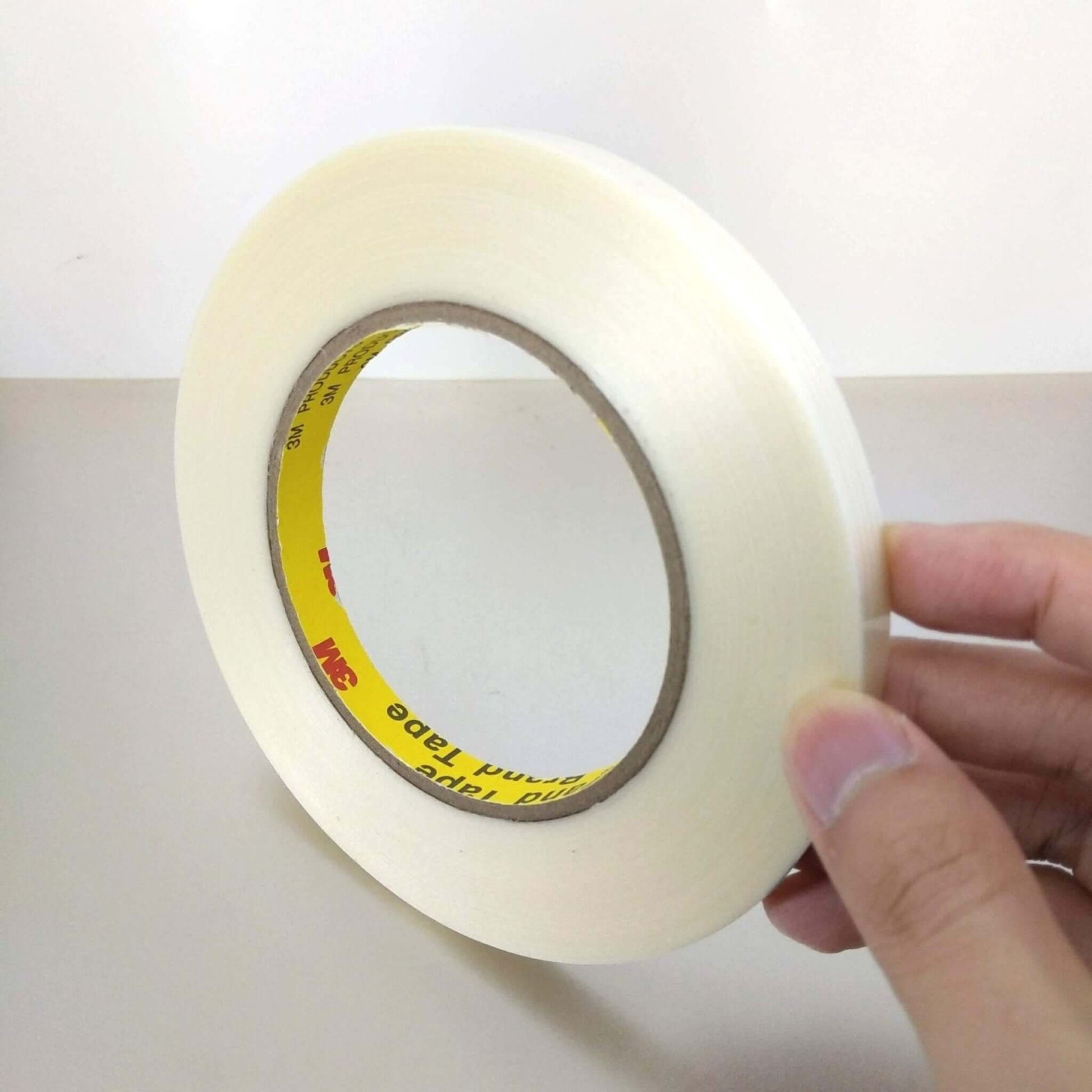 3M 8915 High Strength Fiberglass Filament Tape roll held in hand, sturdy tape for industrial and household use.