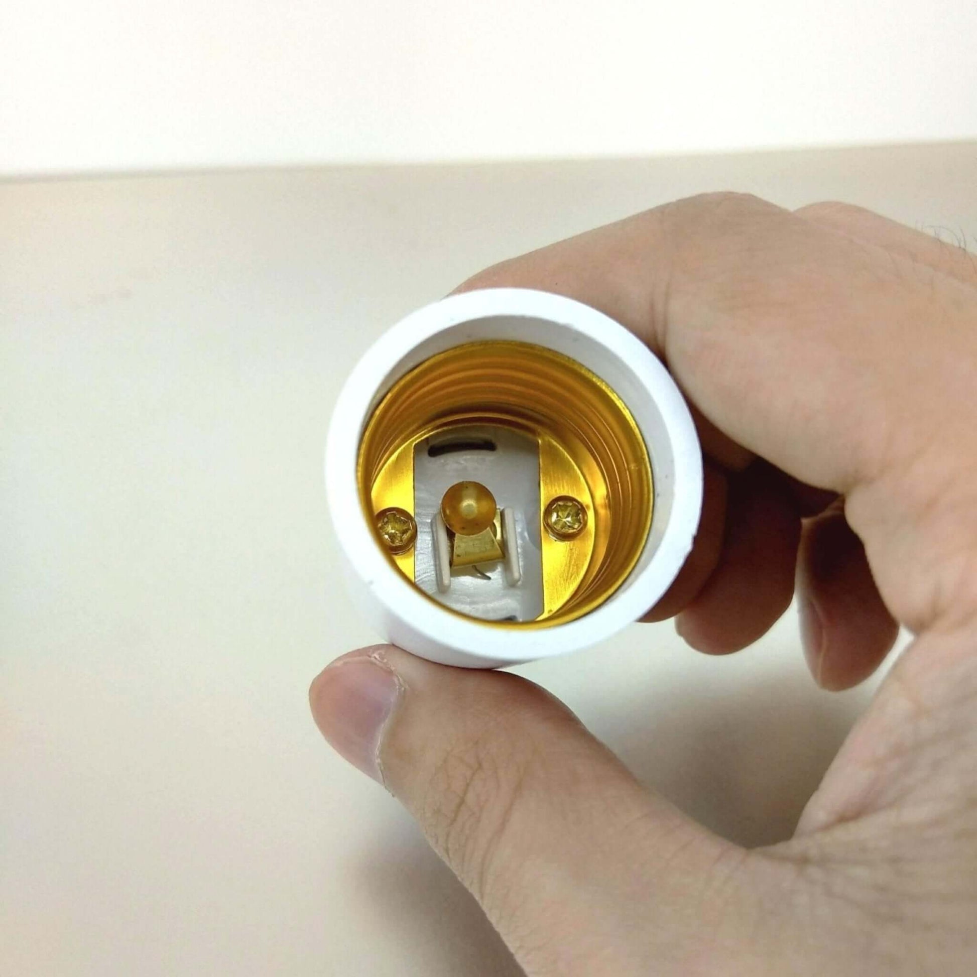 B22 to E27 light socket adapter held in hand, showing interior details for easy bulb conversion.