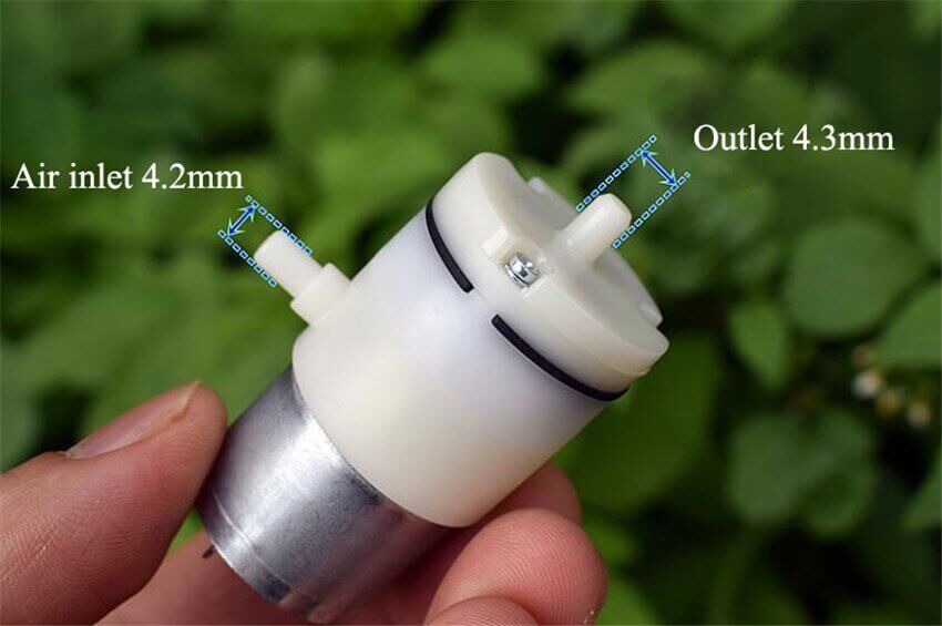 Close-up of a mini vacuum pump with 4.2mm air inlet and 4.3mm outlet, held in hand, showcasing its compact design.