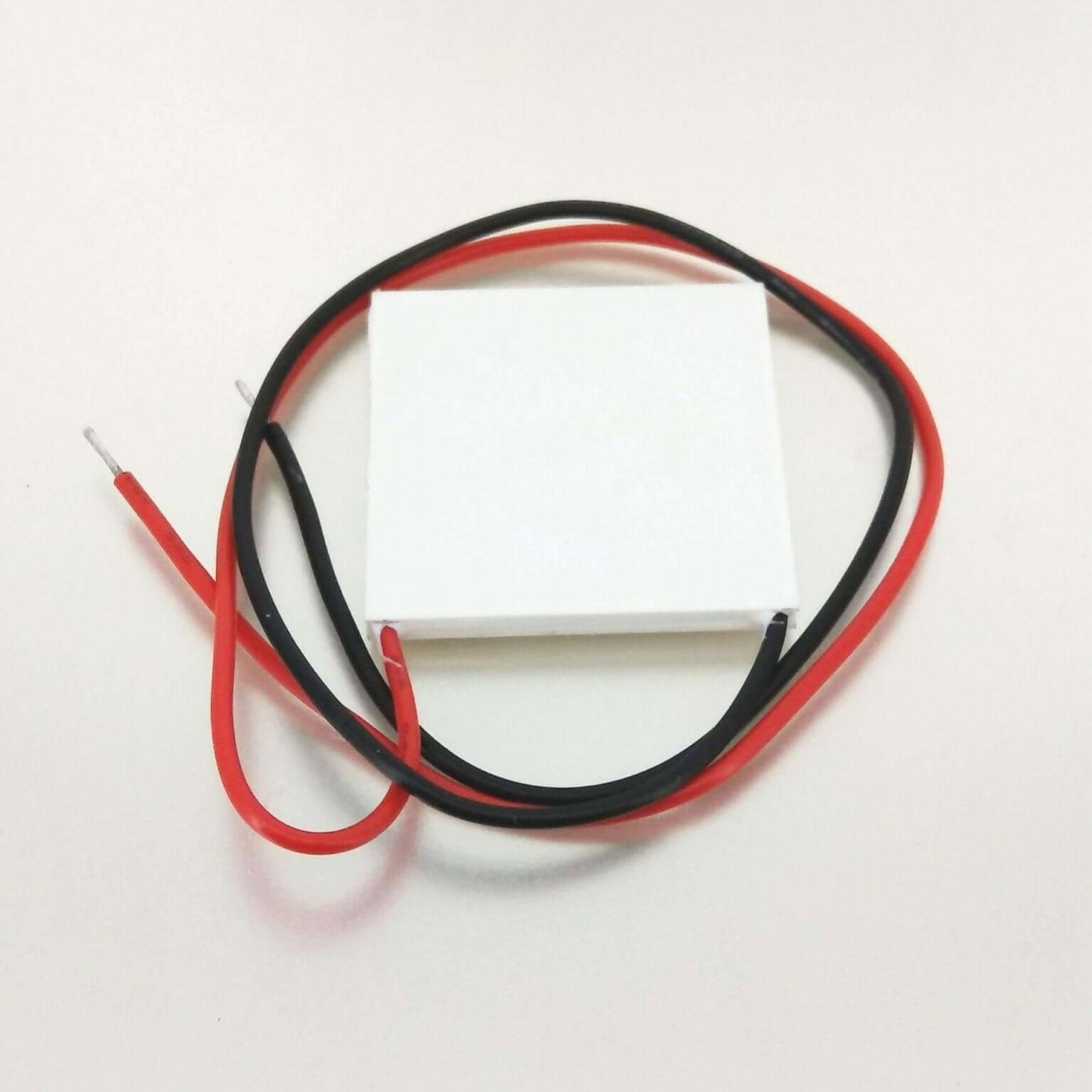 TEC1-12706 Peltier module with red and black wires for thermoelectric cooling or heating applications.