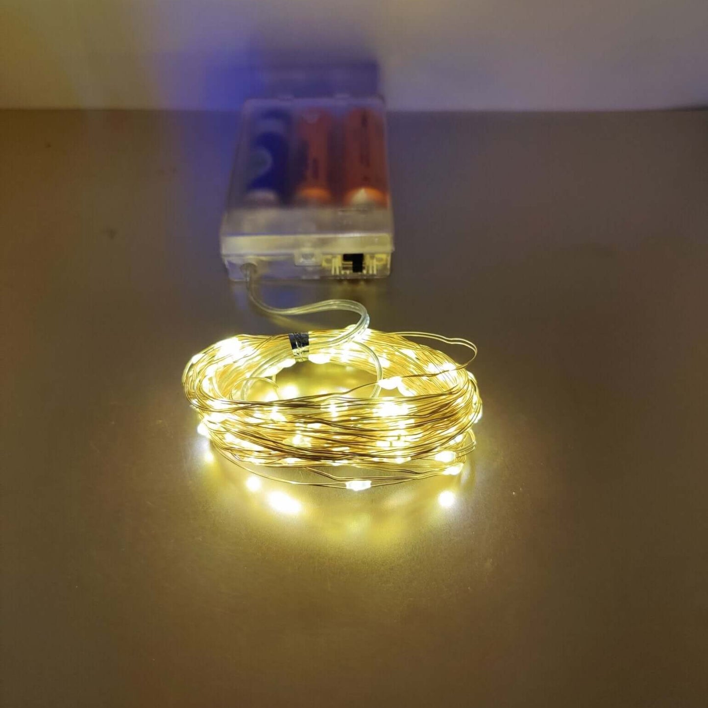 Warm white LED string lights on copper wire with battery pack, perfect for festive indoor and outdoor decorations.
