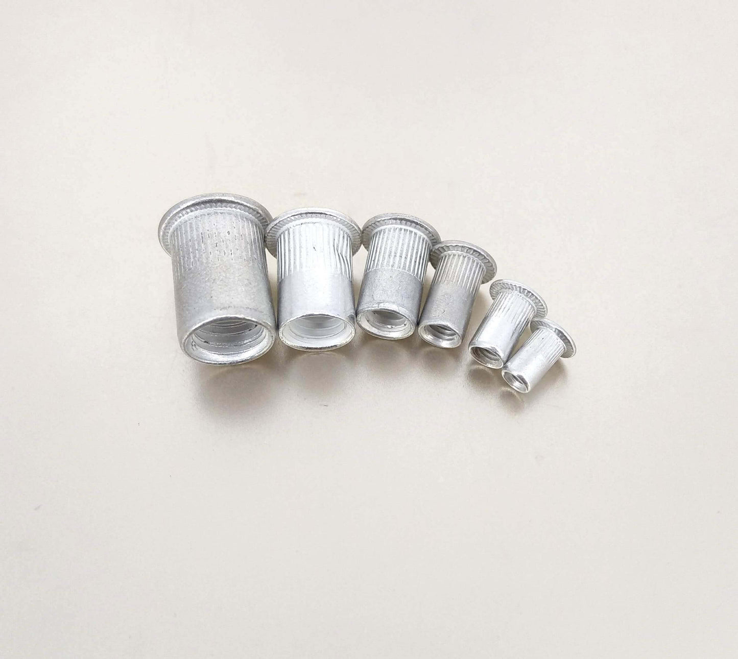 Set of aluminum rivet nuts in various sizes, showcasing M3-M10 threaded inserts for strong fastening solutions.