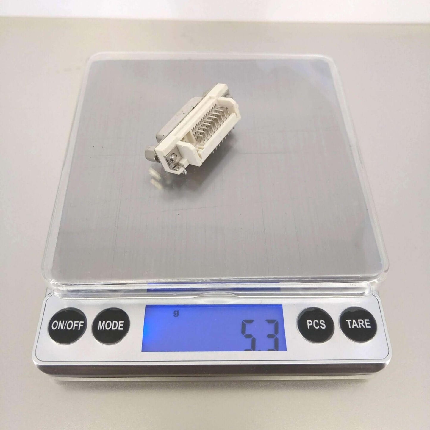 High precision digital pocket scale displaying a weight of 5.3 grams with a small item on the weighing platform.