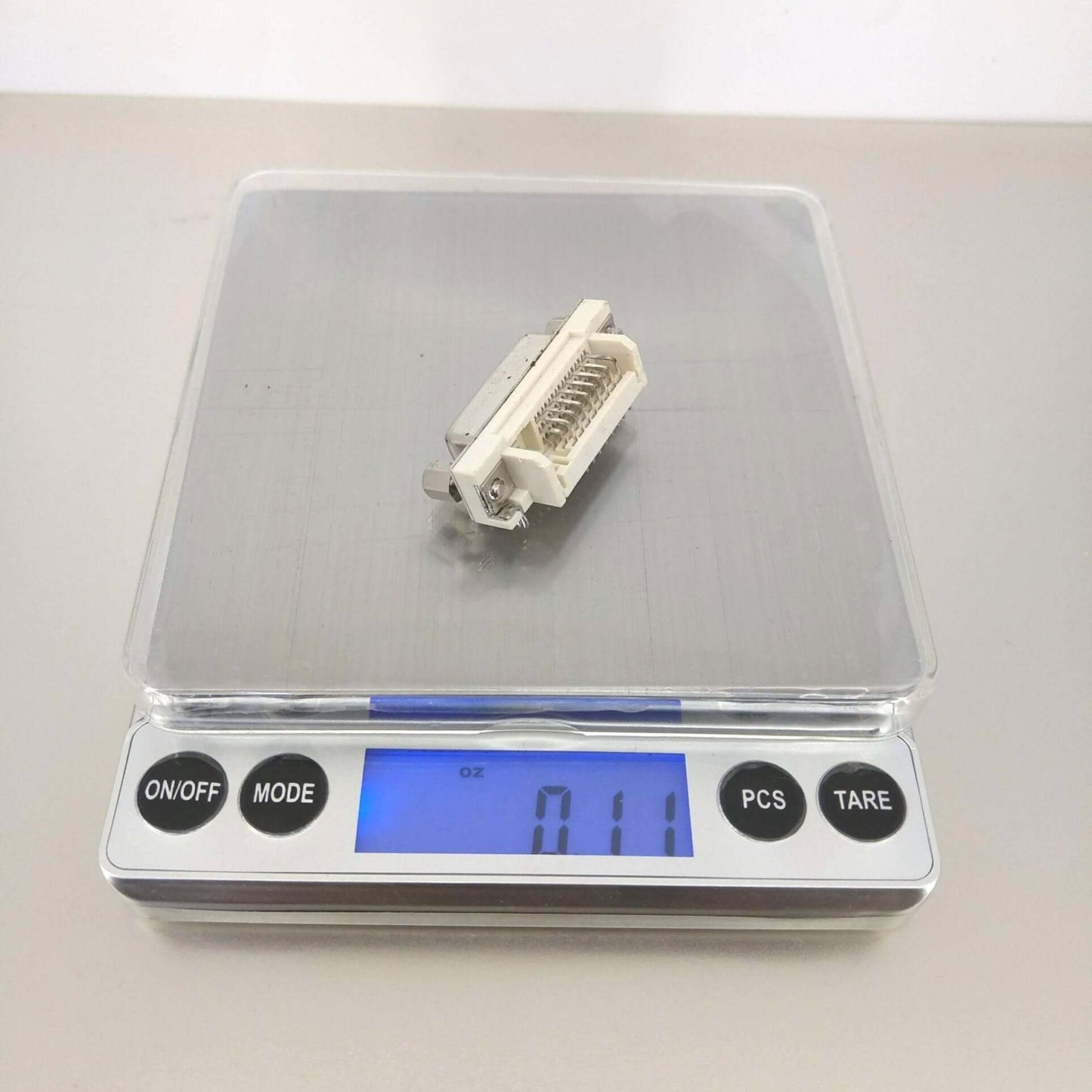 High precision digital pocket scale displaying 0.1 oz measurement of a small object with clear interface.