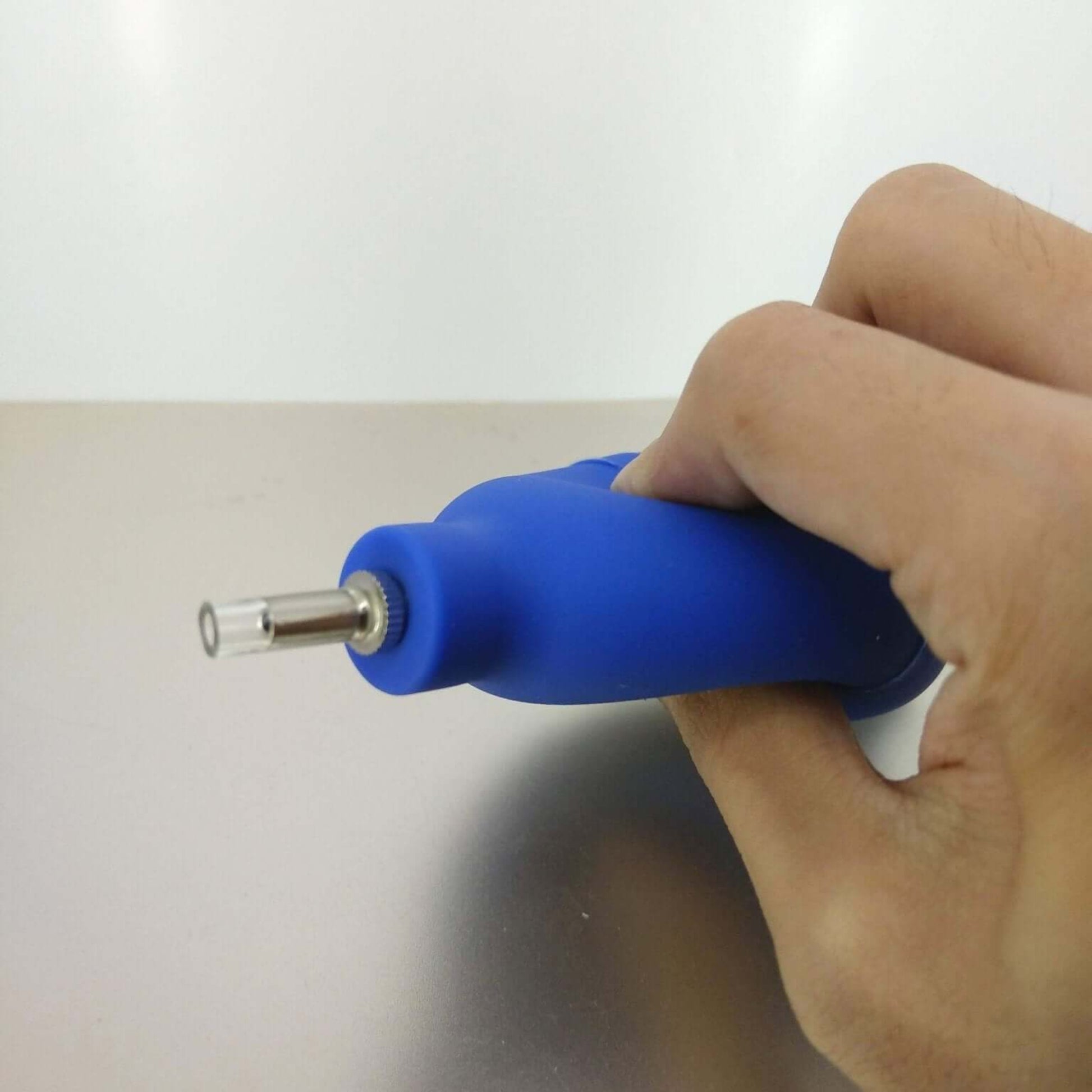 Hand holding a blue mini rubber dust blower ball, ideal for cleaning camera lenses and keyboards.