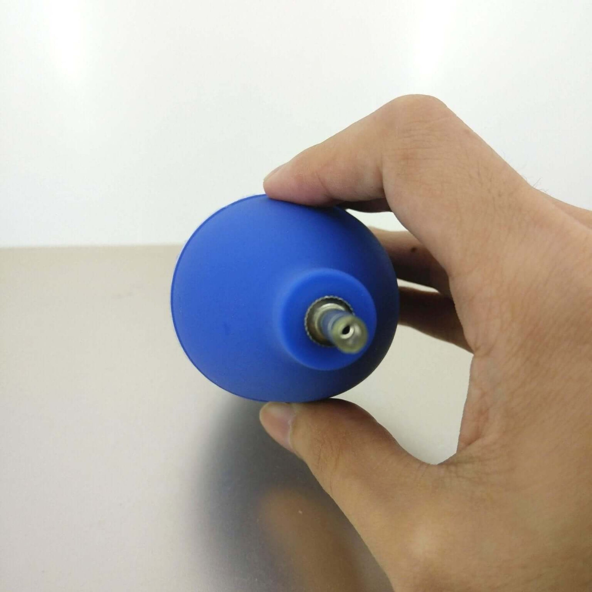 Blue mini dust blower ball being held, ideal for cleaning camera lenses and keyboards.