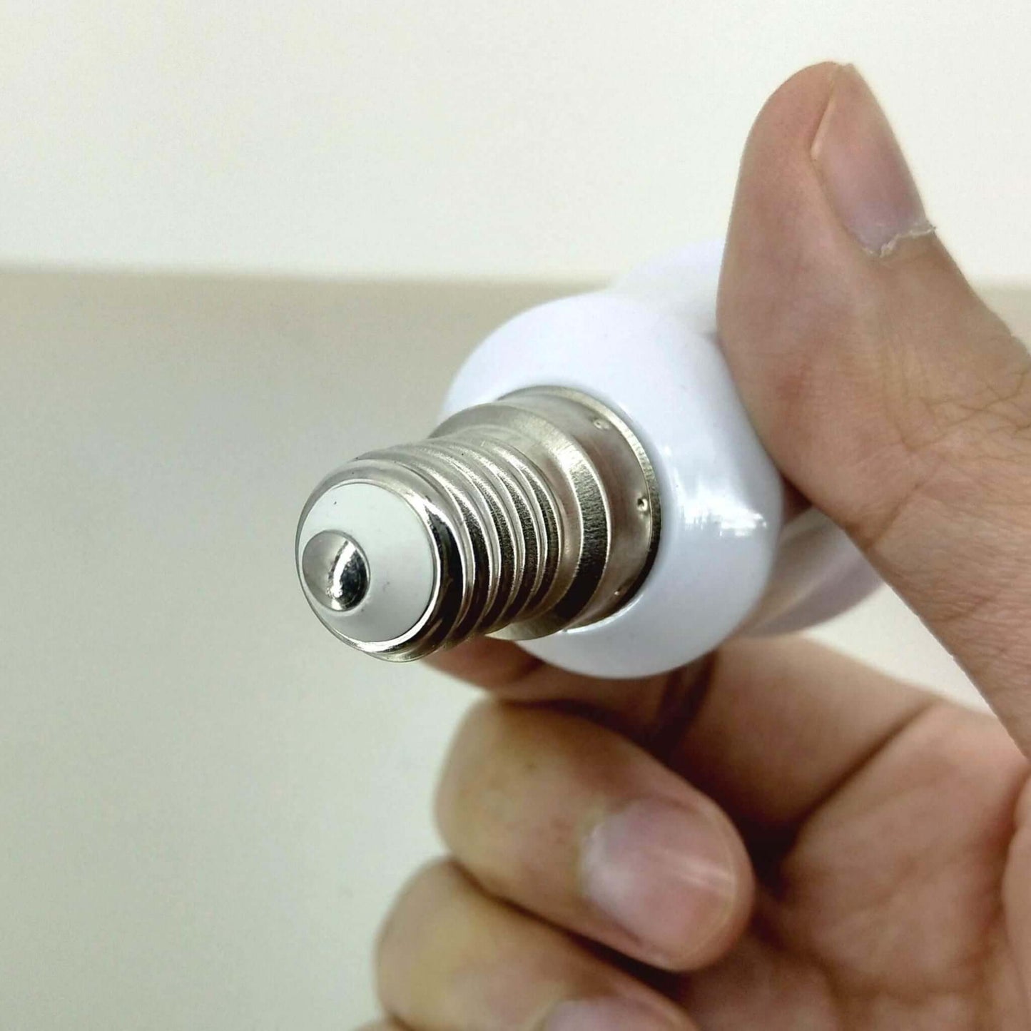 Hand holding E14 lamp holder showing small screw base for converter adapter.