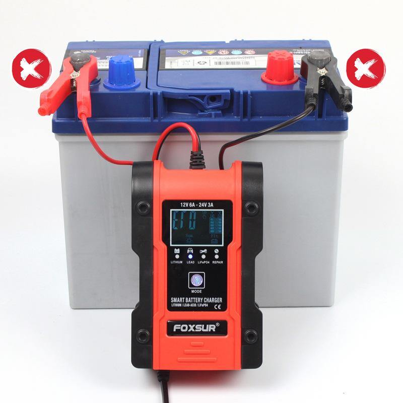 FOXSUR smart battery charger connected incorrectly to a car battery, with red 'X' marks over the clamps indicating a reverse polarity connection error.