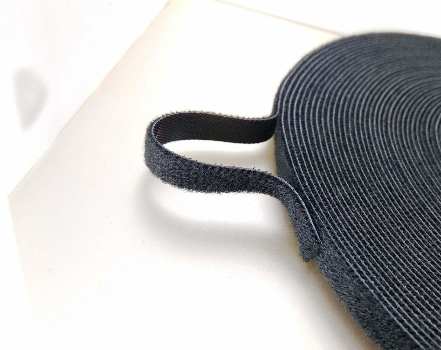 Close-up of 1cm x 25m self-adhesive hook and loop fastener cable tie for organizing cables and wires.