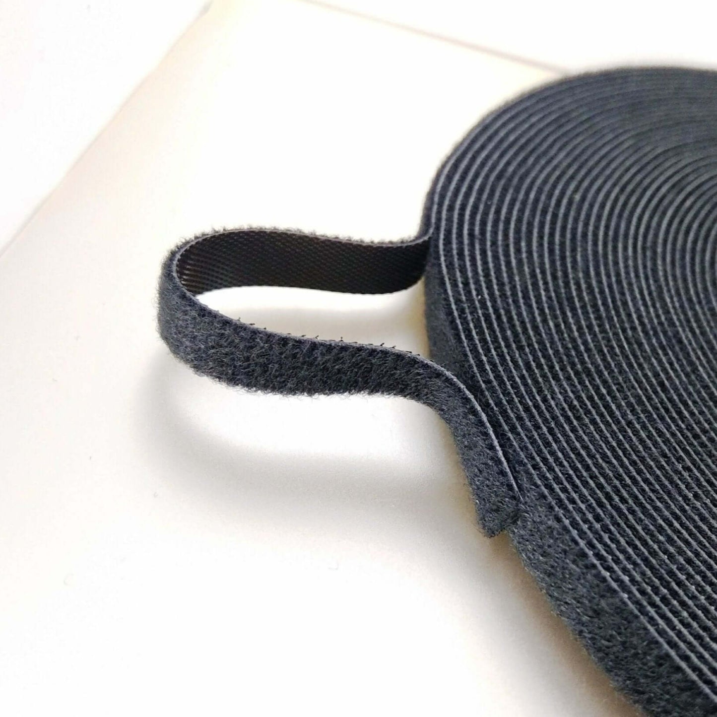 Close-up of 1cm x 25m self-adhesive hook and loop fastener cable tie for organizing cables and wires.