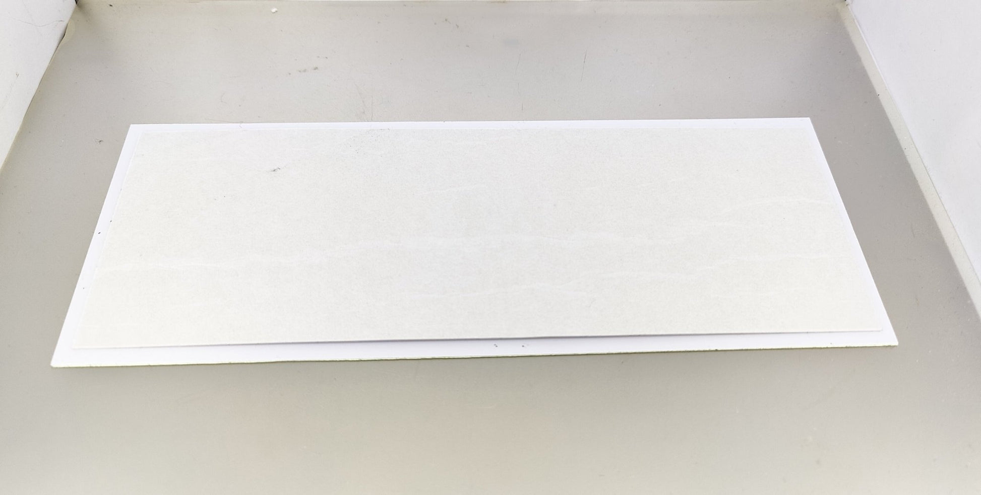 Plain white adhesive back of the luminous security camera warning sticker, ready for application.