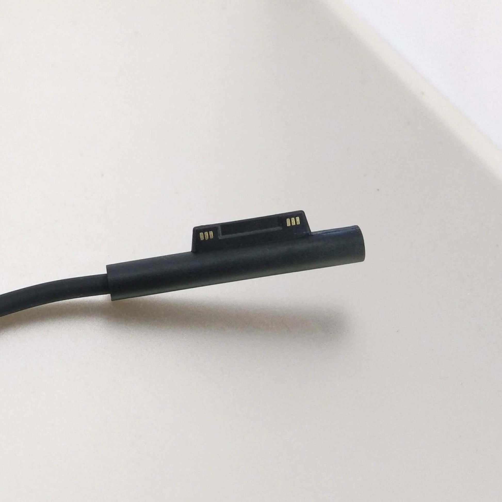 Close-up of Surface charger connector for Microsoft Surface devices, ensuring reliable power connection.