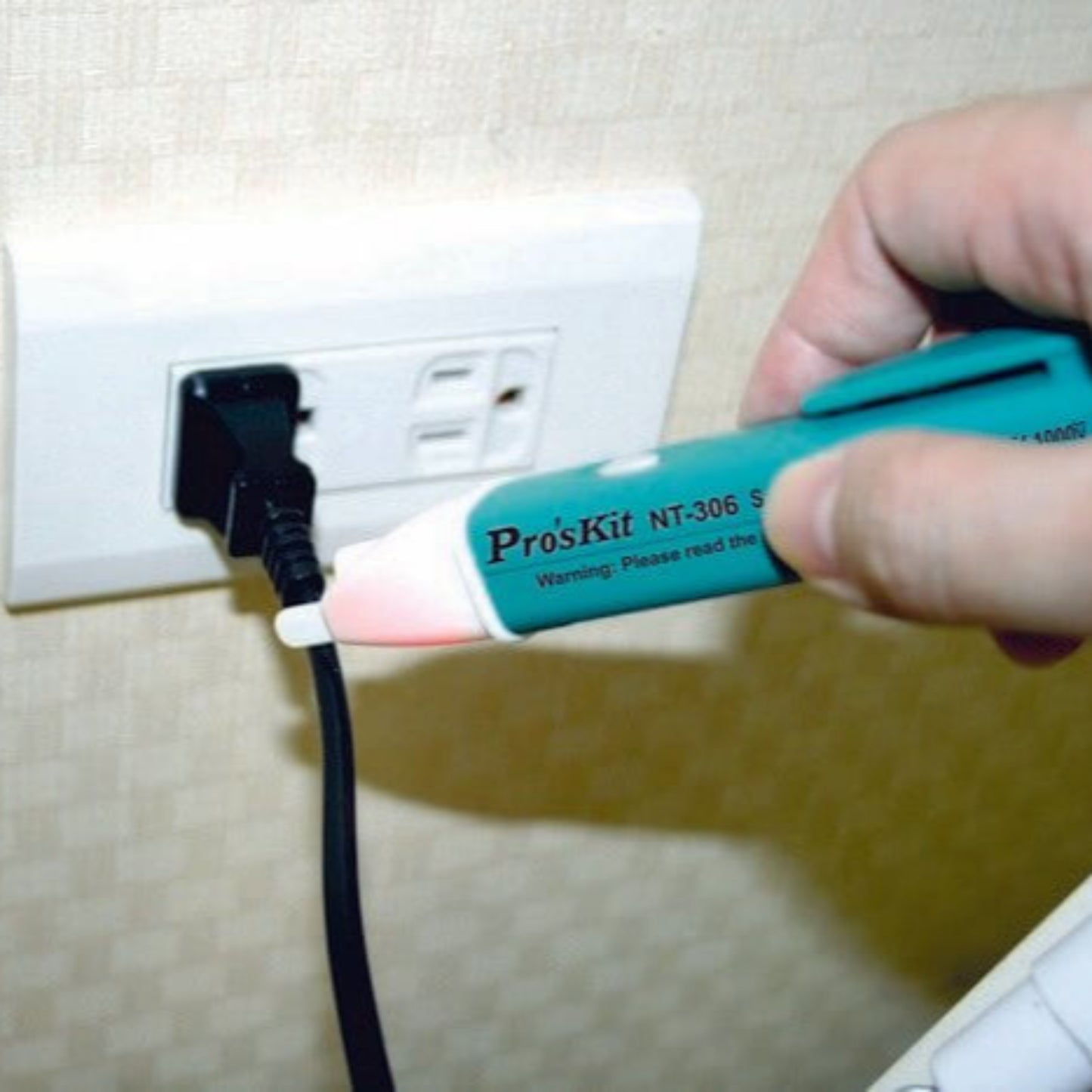 Pro'sKit NT-306 non-contact voltage detector pen testing an electrical outlet for safety.