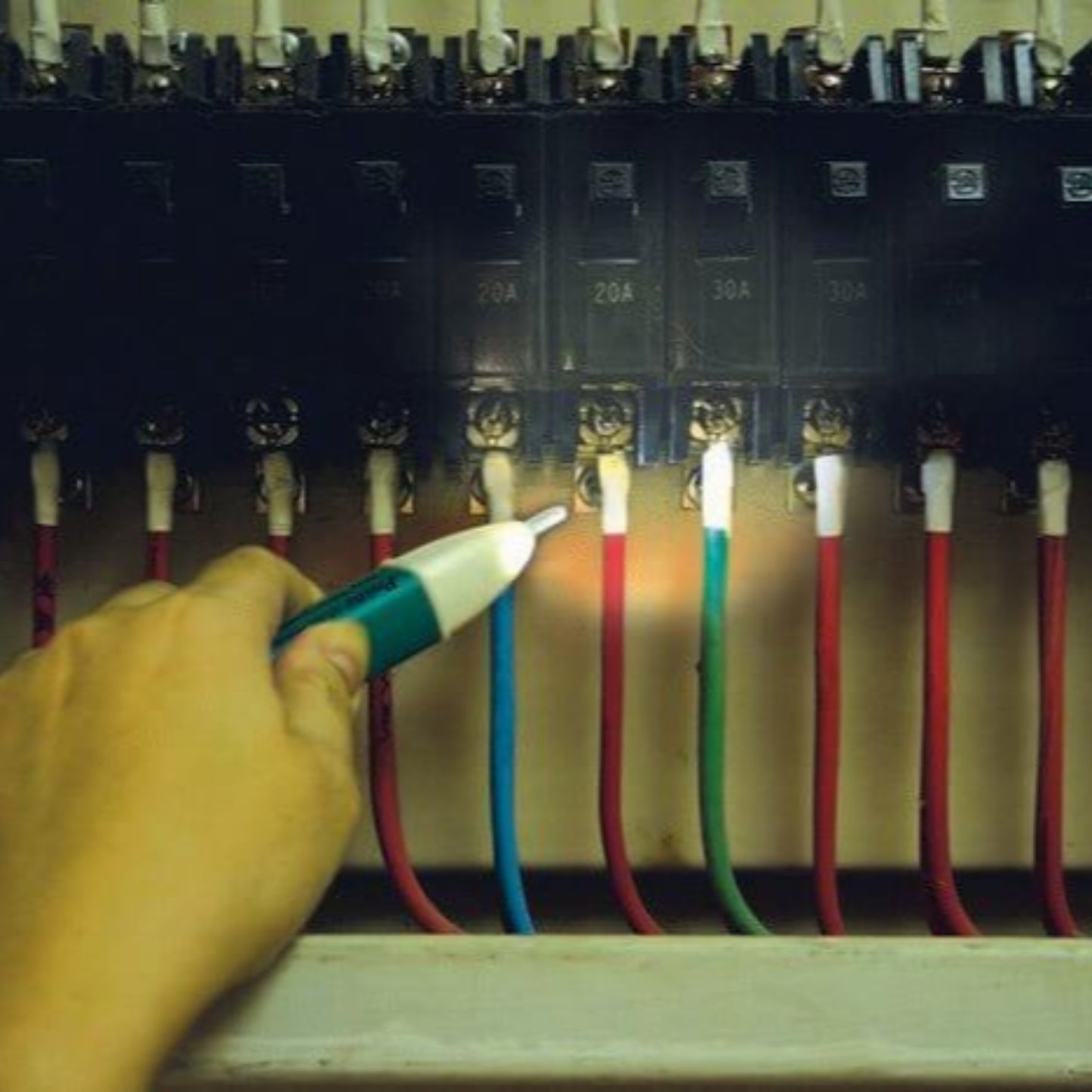 A hand using the Pro'sKit NT-306 non-contact voltage detector on a circuit breaker panel.