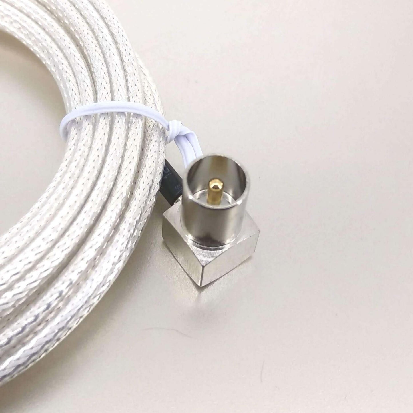 Detail of a right-angle coaxial connector on a white antenna cable, ideal for tight spaces.